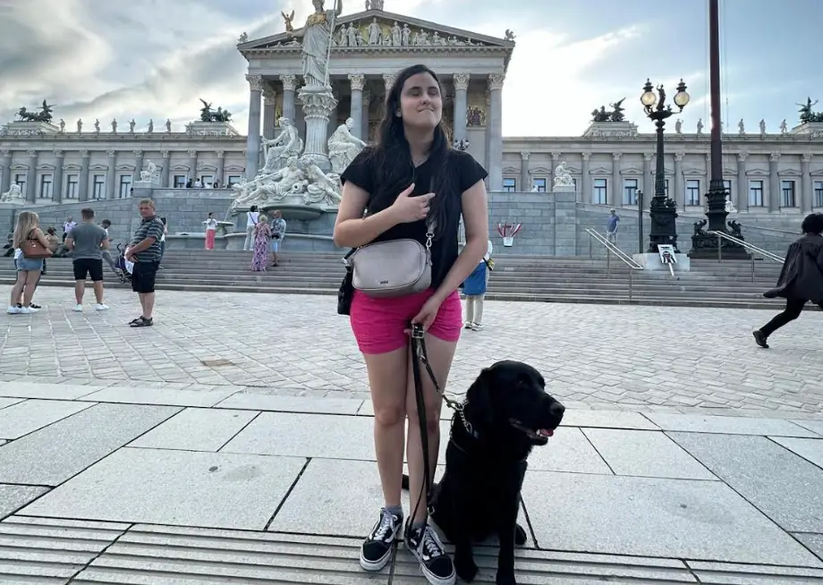 The writer and her guide dog standing in front of a monument.
