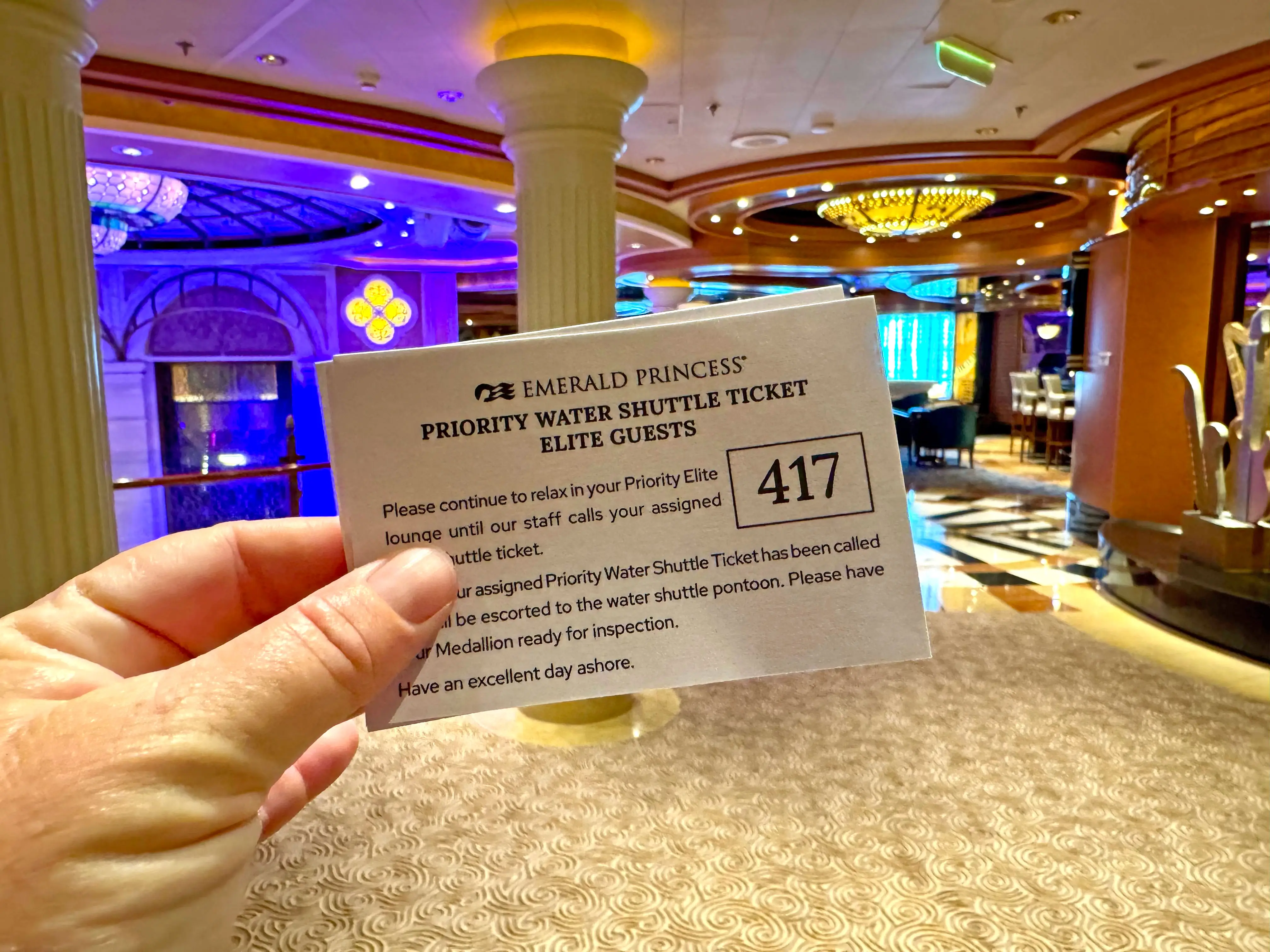 A person holds a priority water shuttle ticket for Elite guests.