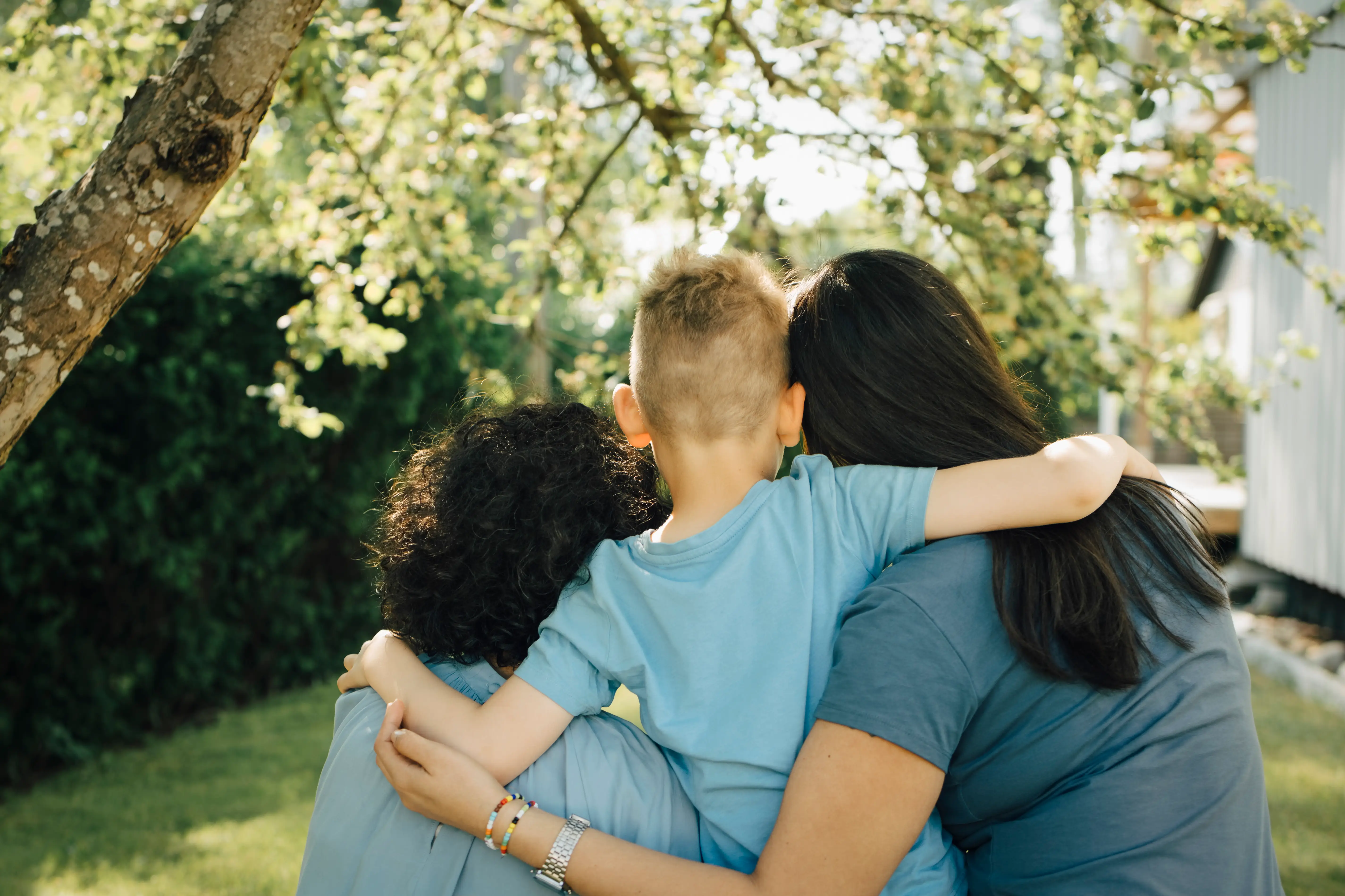 A woman hugs her two sons.