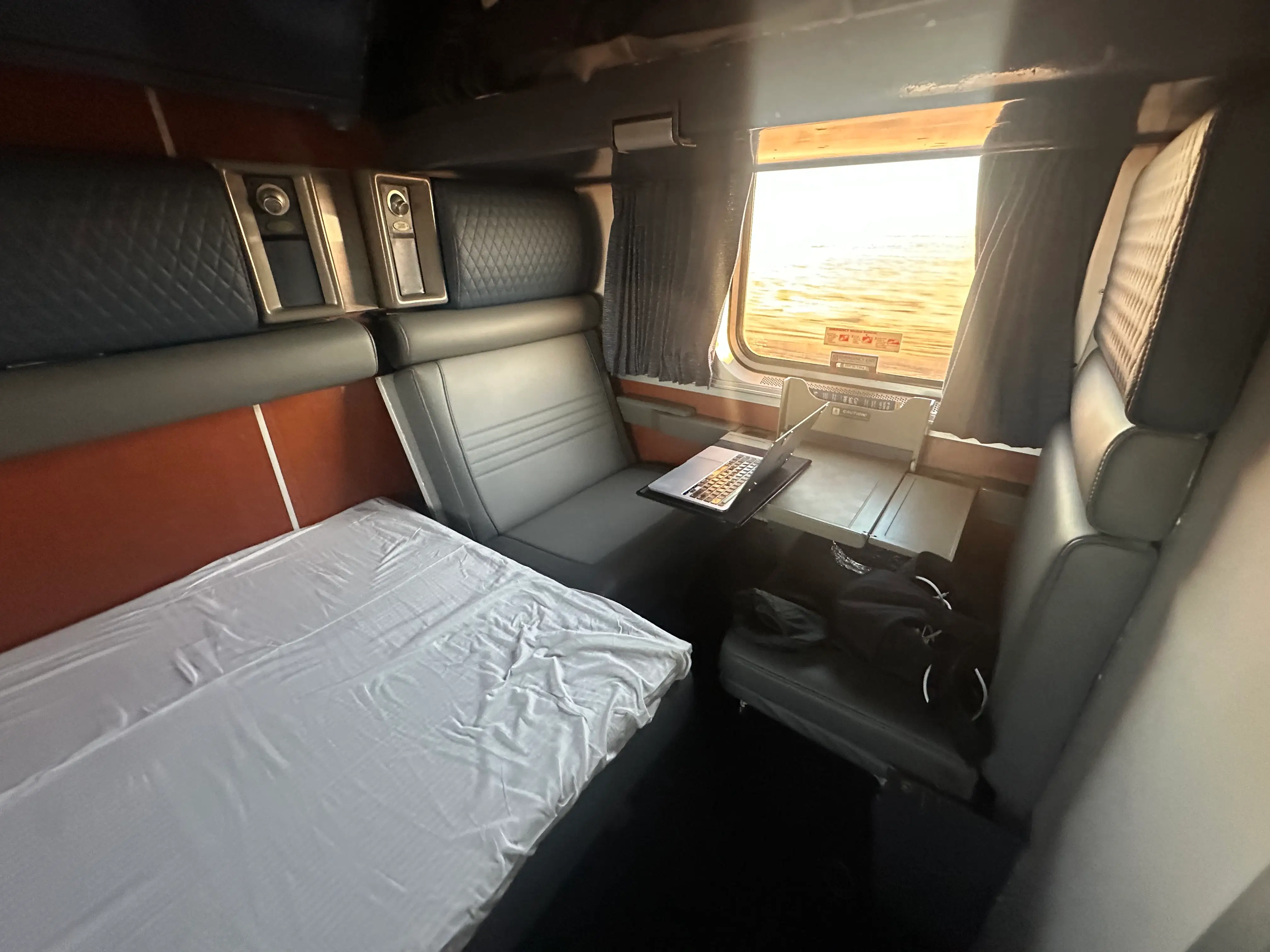 Amtrak sleeper car room with bed and table.