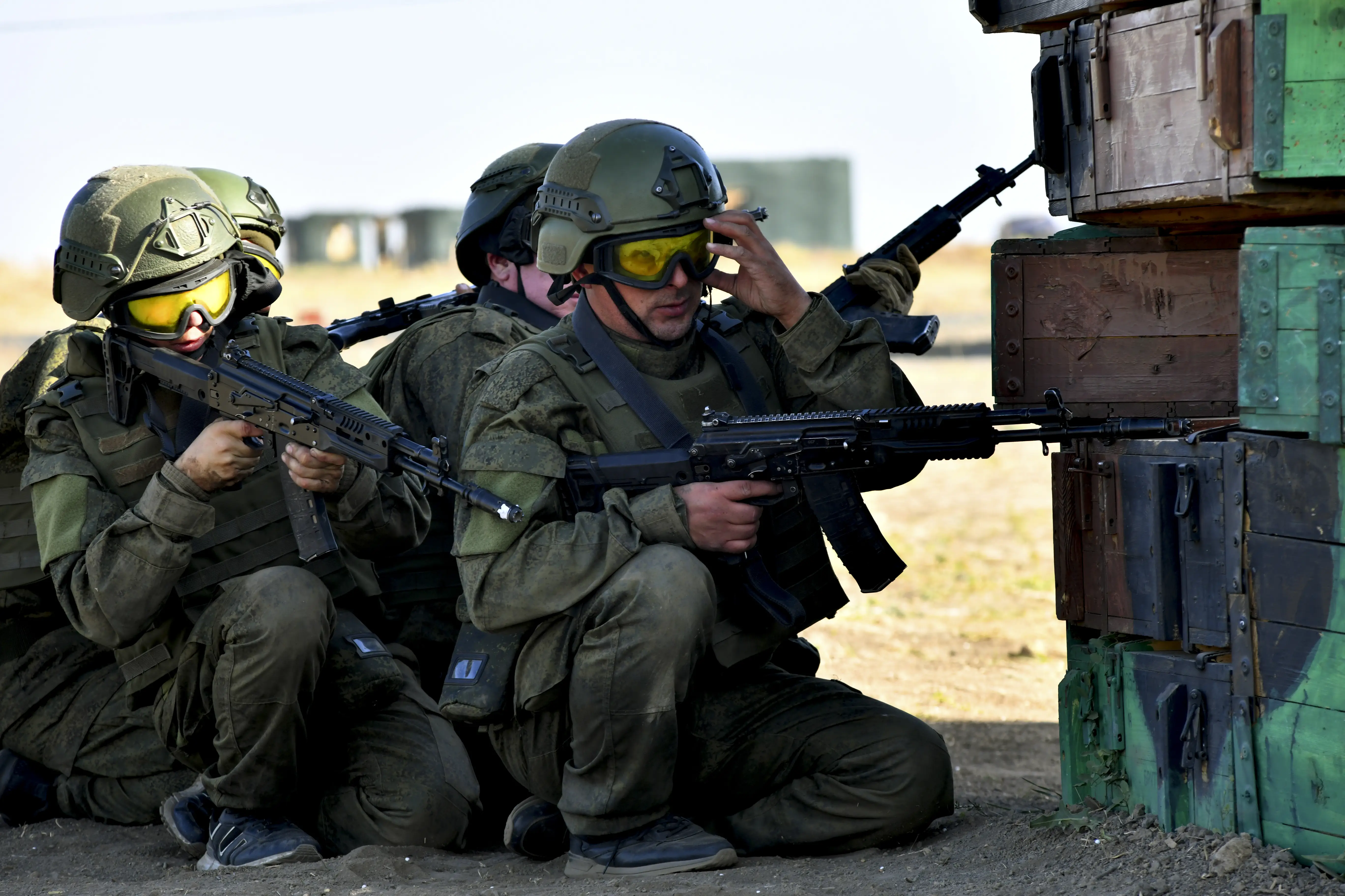 Four Russian contract servicemen crouch behind cover with their rifles during a trainnig exercise.