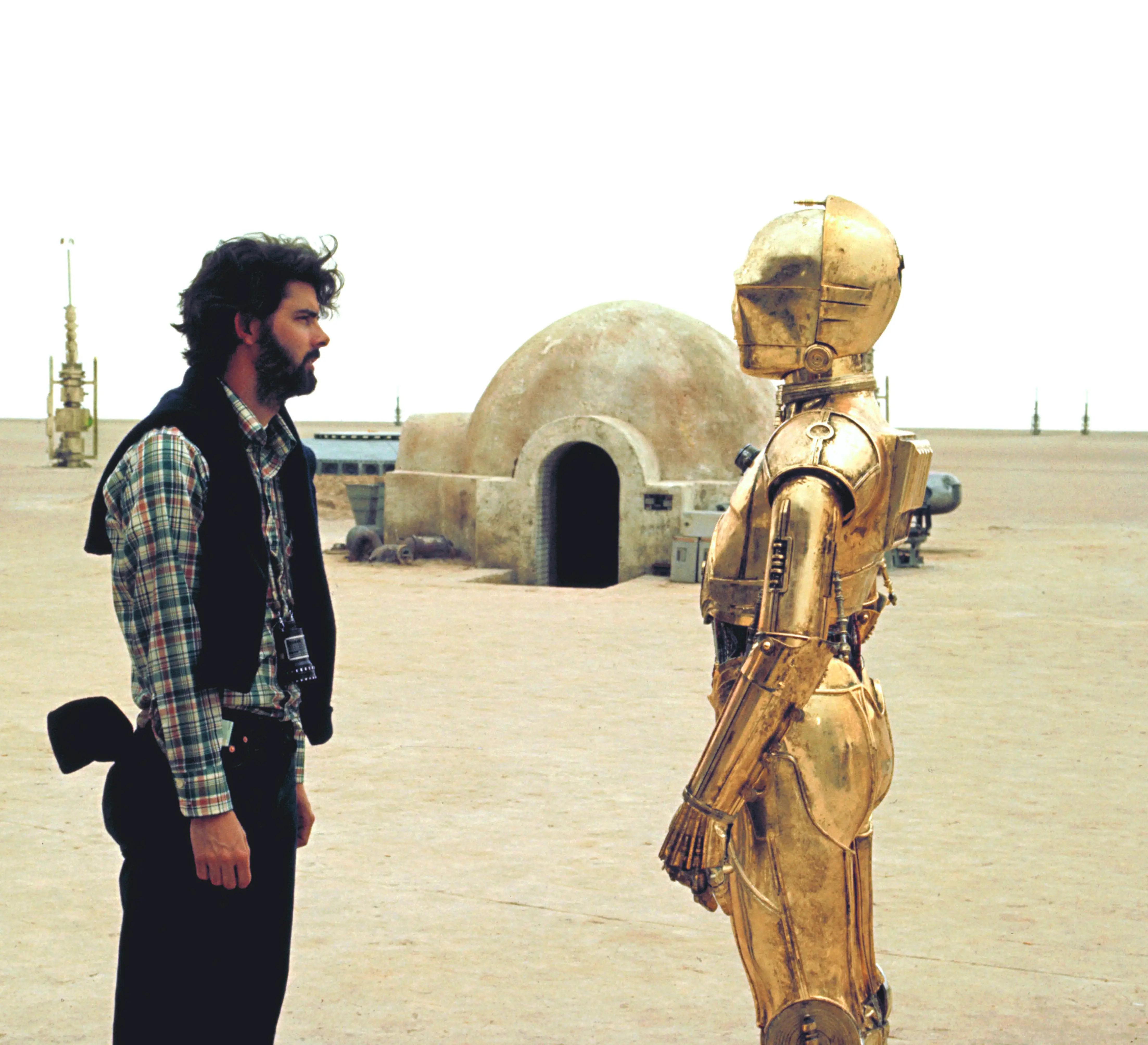 George Lucas standing with C3PO on the set of Star Wars