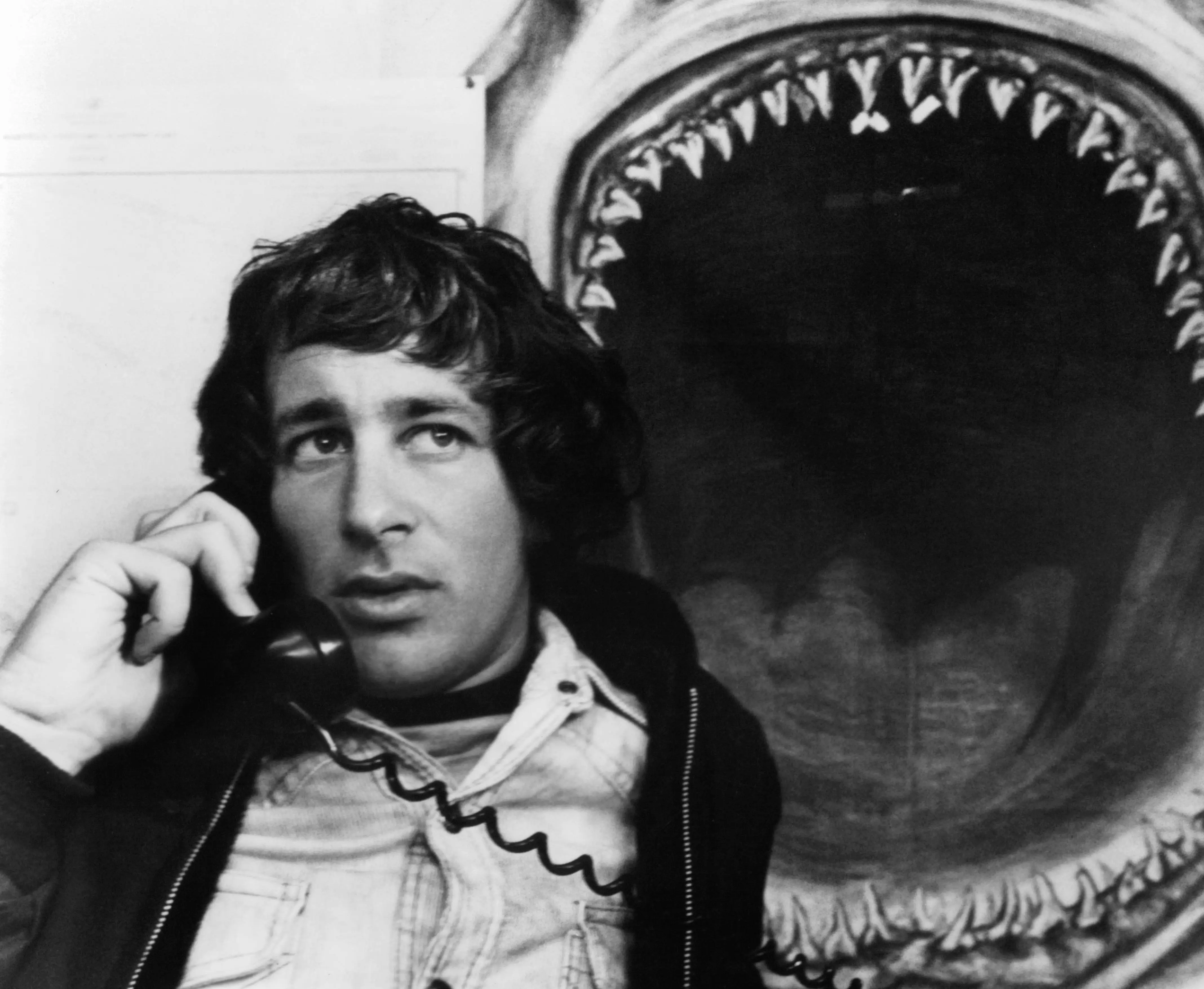 Steven Spielberg on the phone next to a photo of a shark with mouth wide open