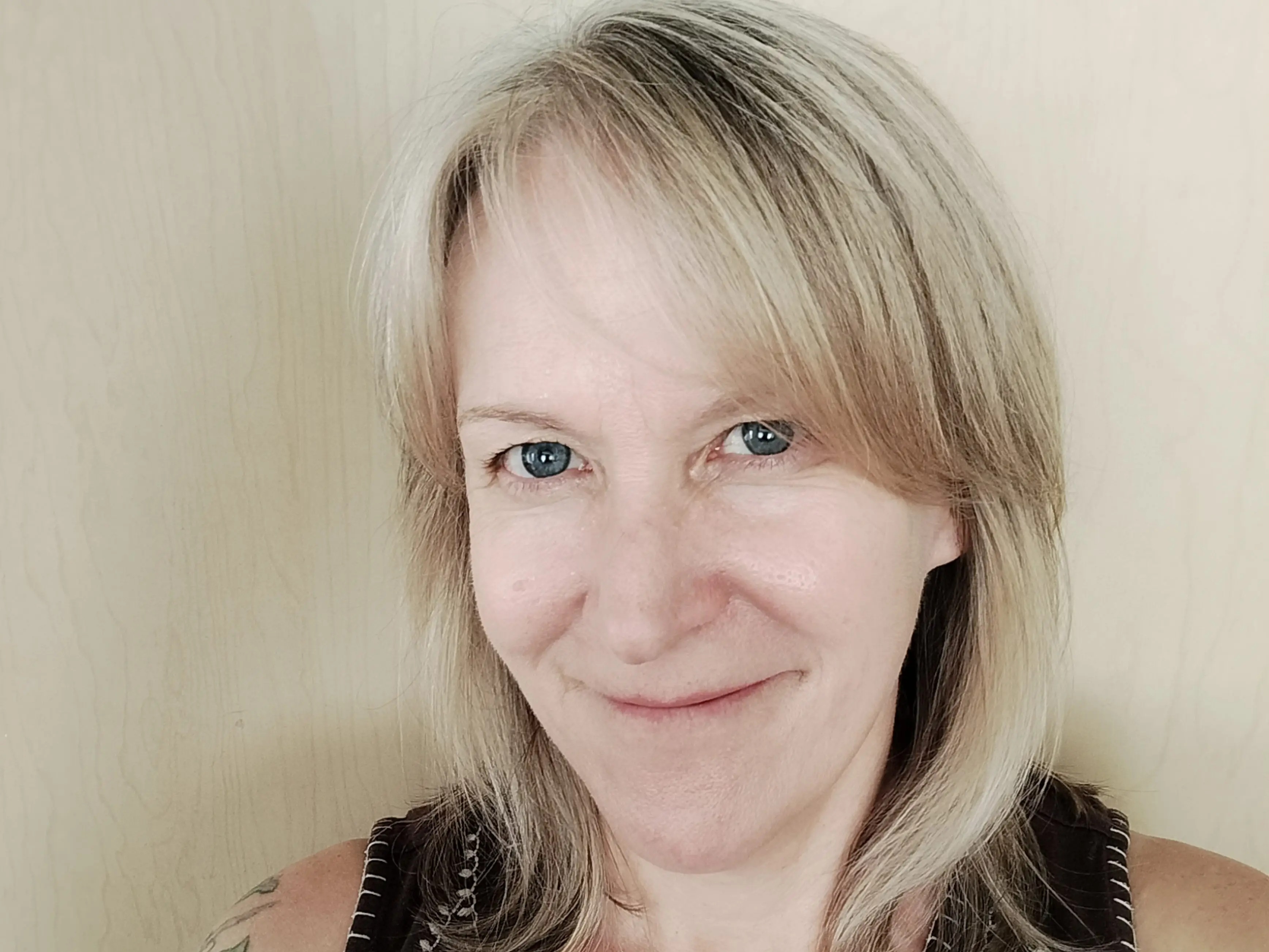 The author poses in front of a light-colored wall.