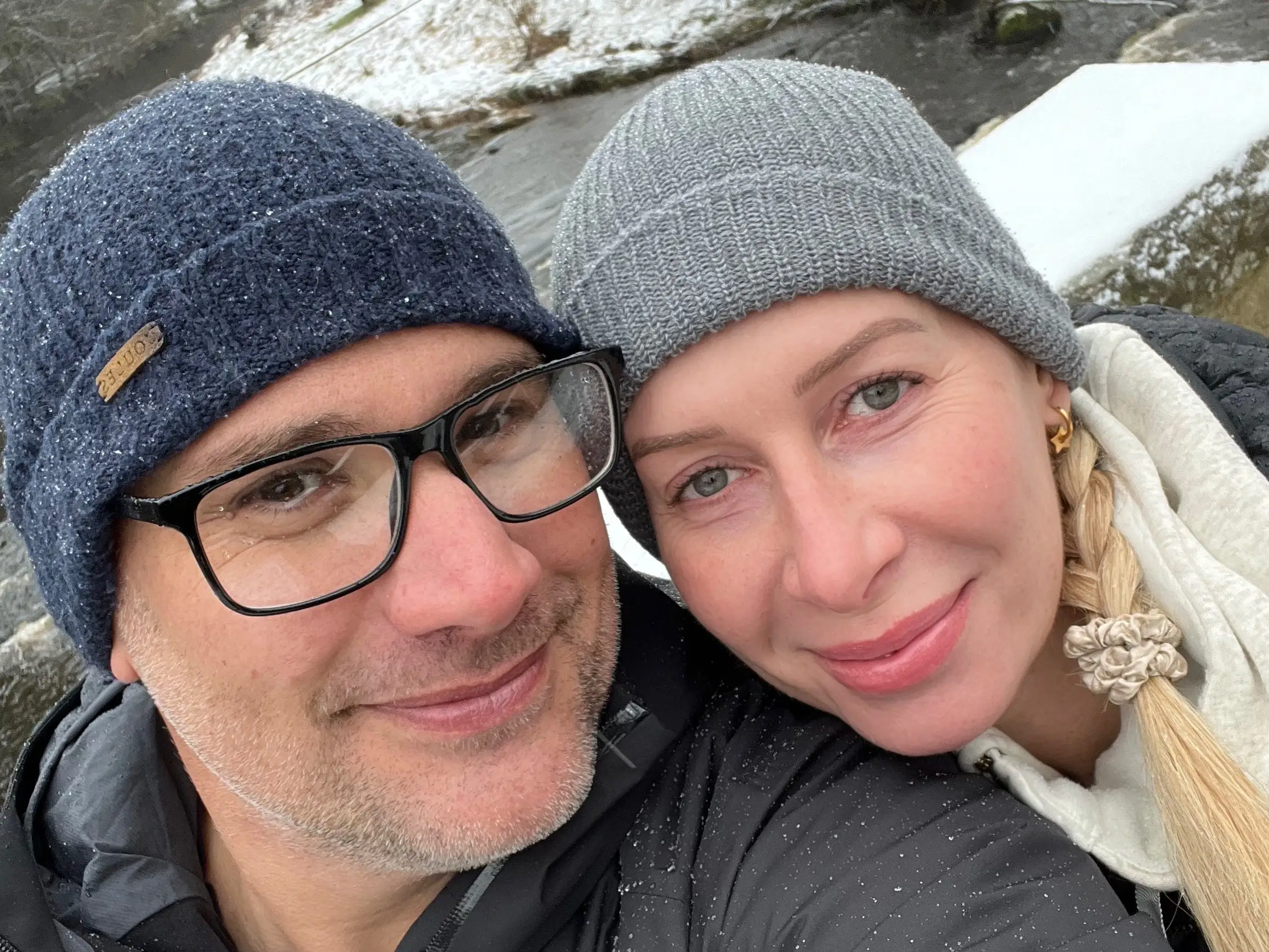 a man and woman posed for a selfie with a snowy background