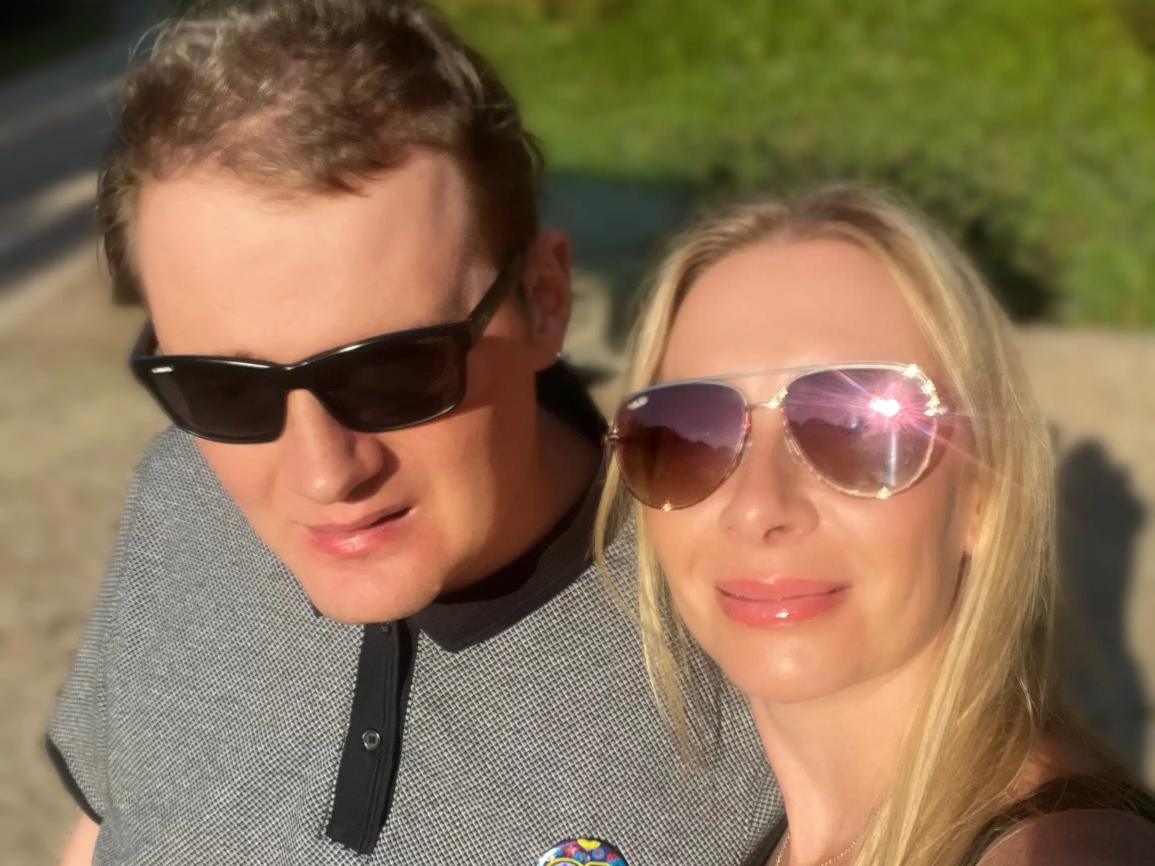 a woman and man in sunglasses taking a selfie outside.