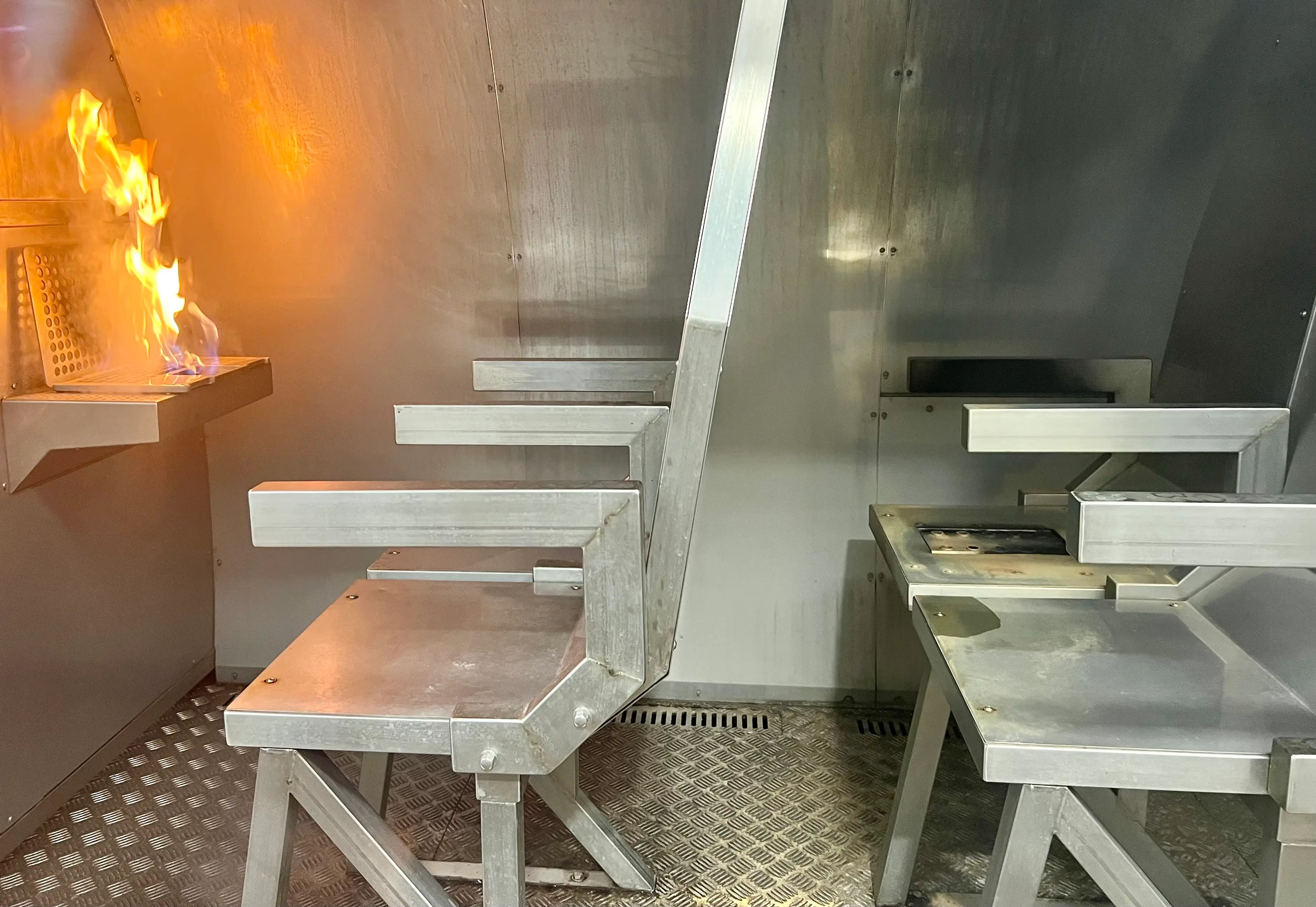 A model of a laptop is on fire in a metal mockup cabin as part of training for Air New Zealand flight attendants