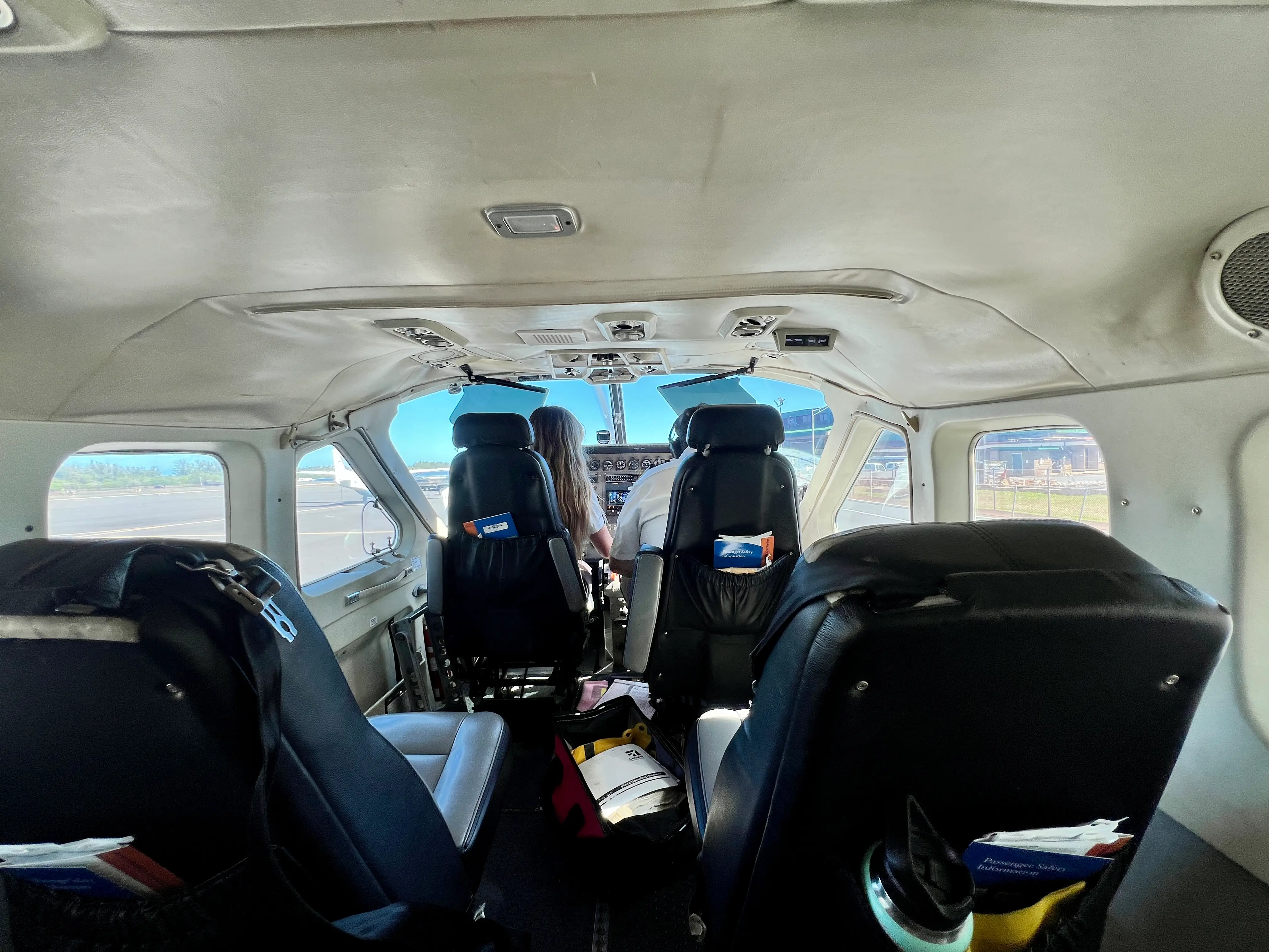 Four leather seats, front row with people in them, on small plane