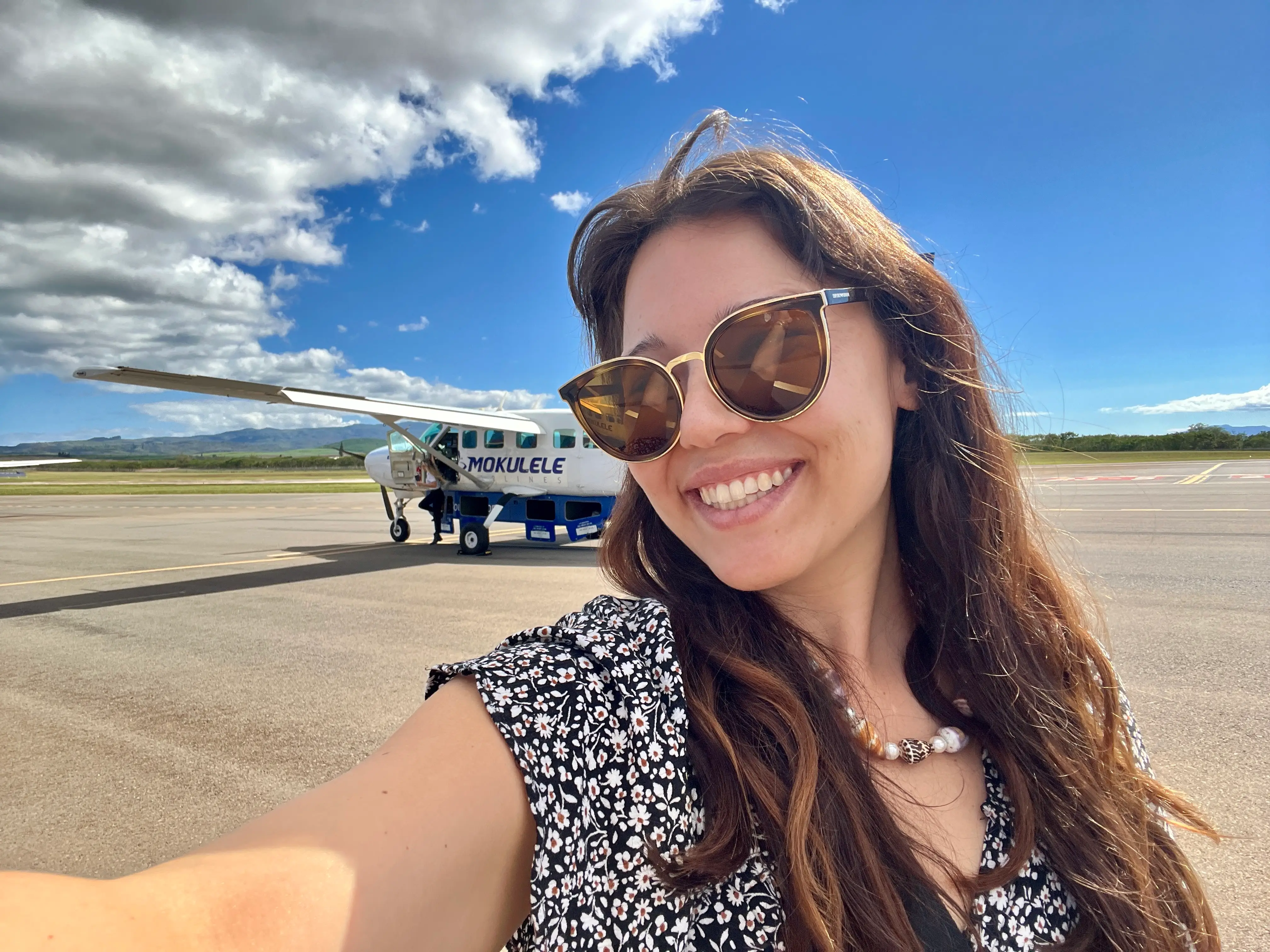 Author Ashley Probst smiling in front of Mokulele plane in selfie