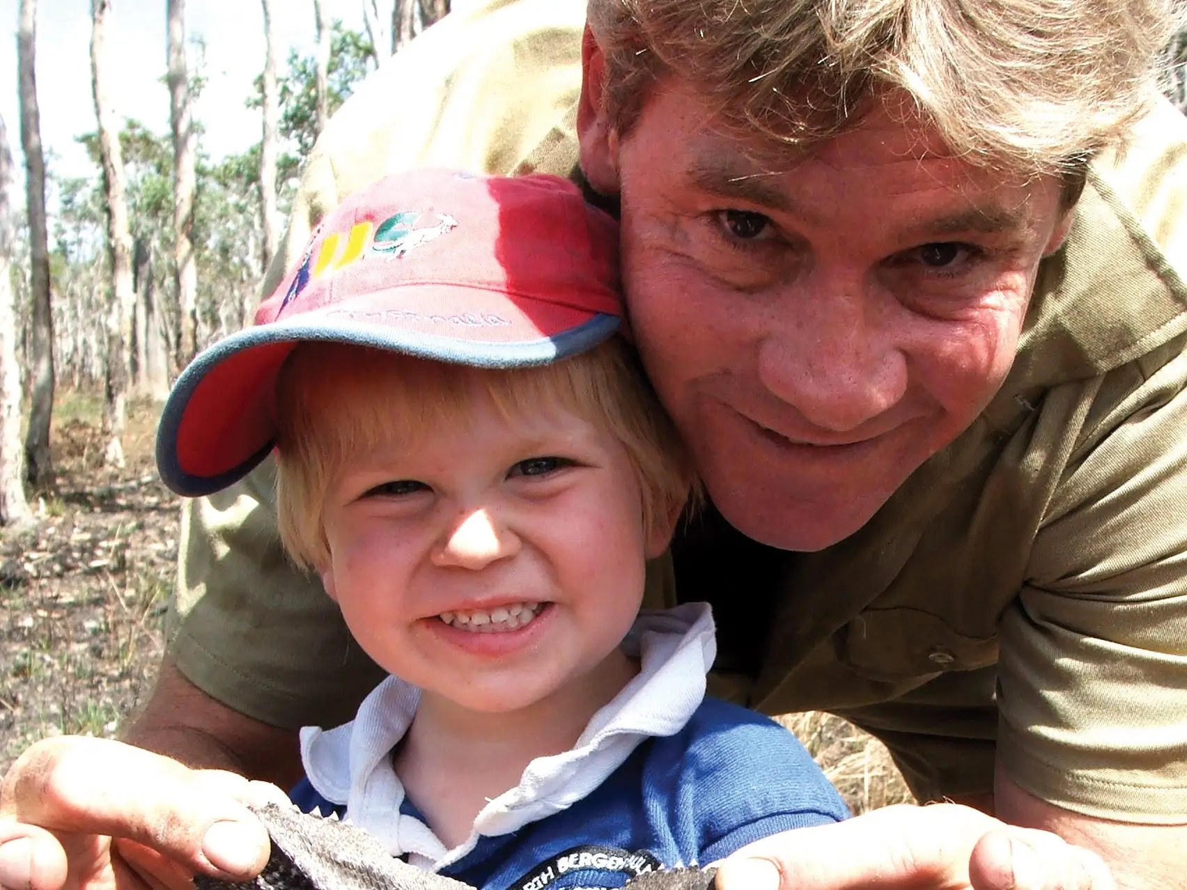 Steve Irwin and his son, Robert Irwin, holding up a small reptile.
