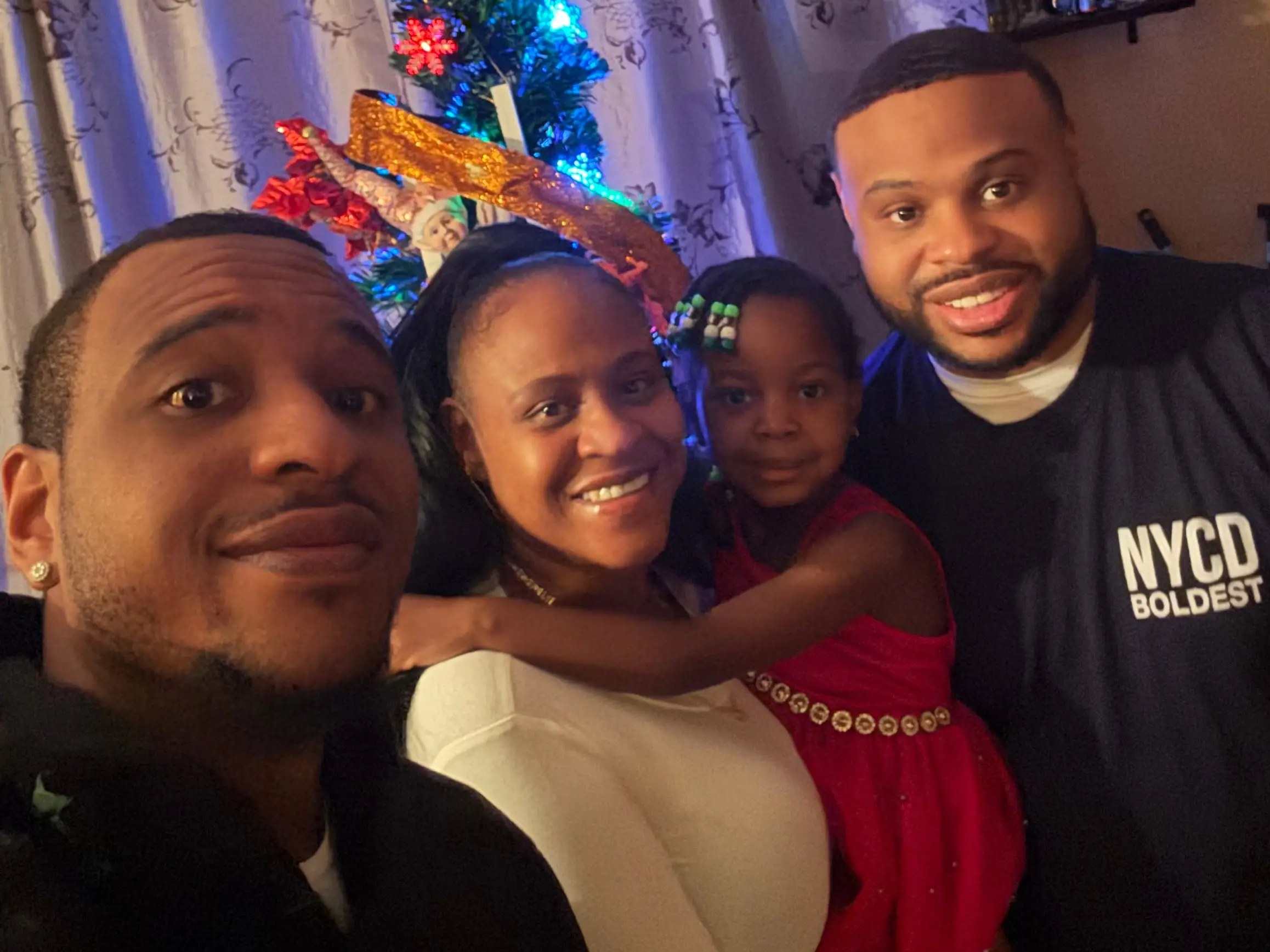 A family of four standing in front of a Christmas tree.