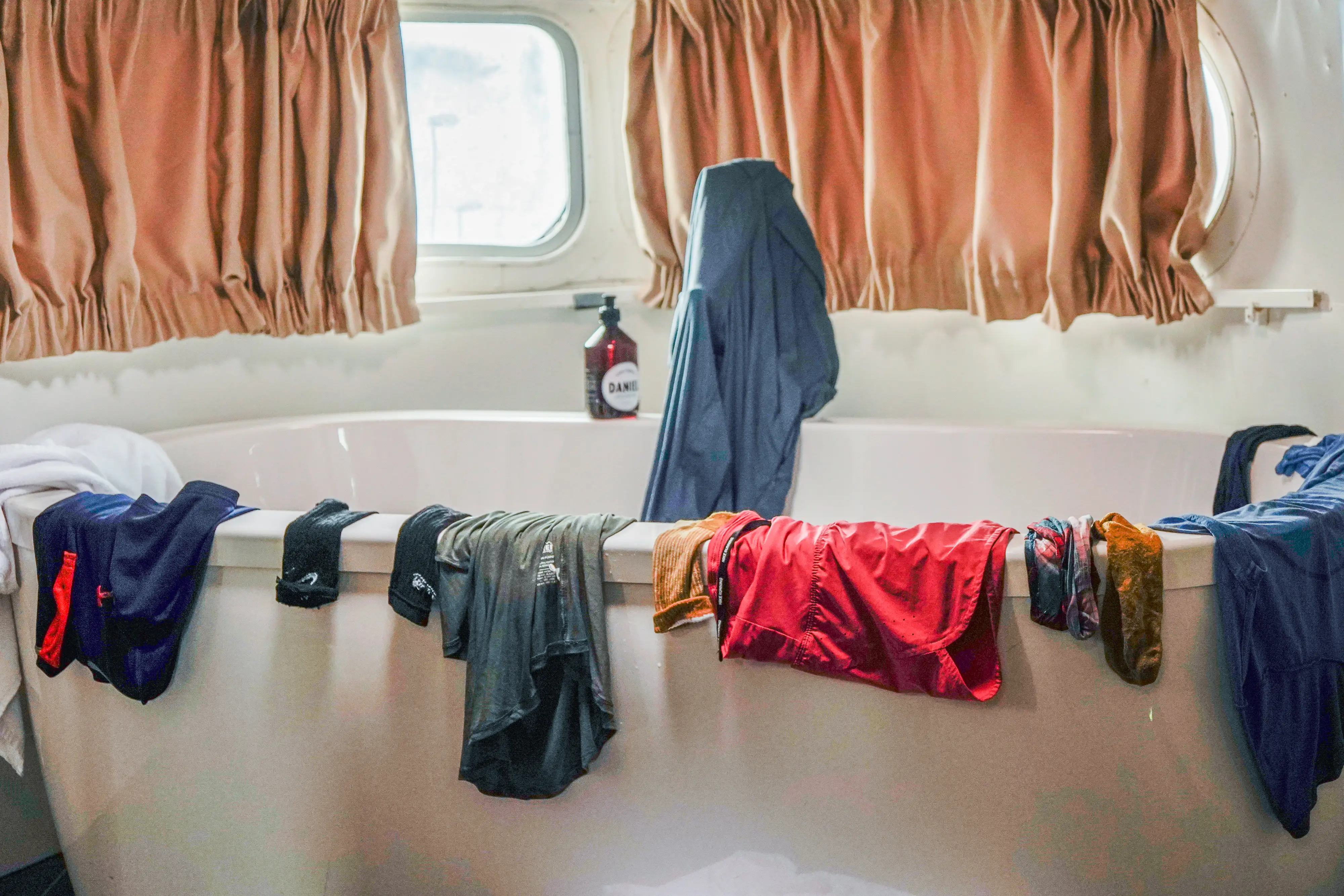 wet clothes hang on the side of a stand-alone tub