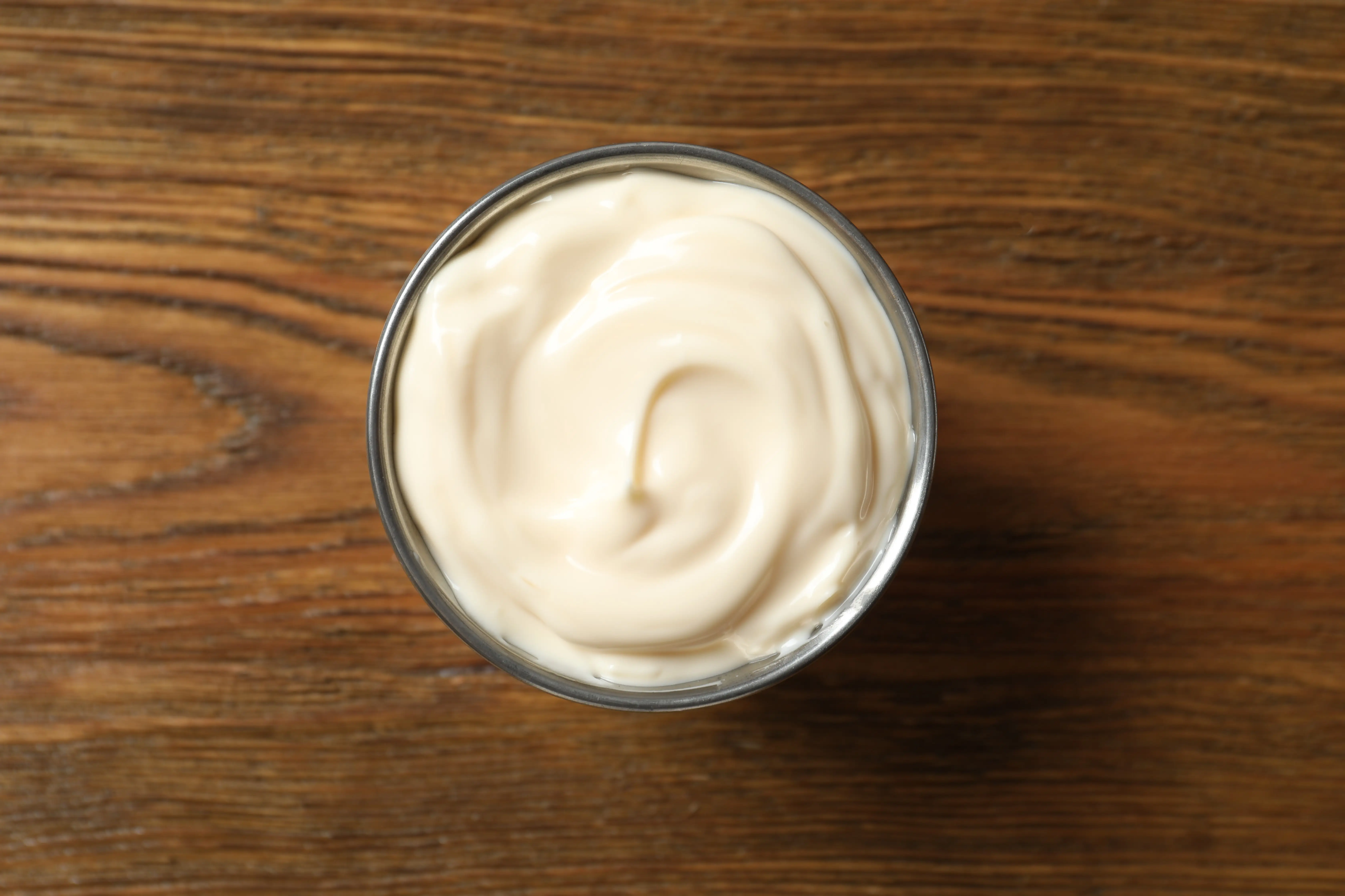 Bowl of mayonaise on wood background