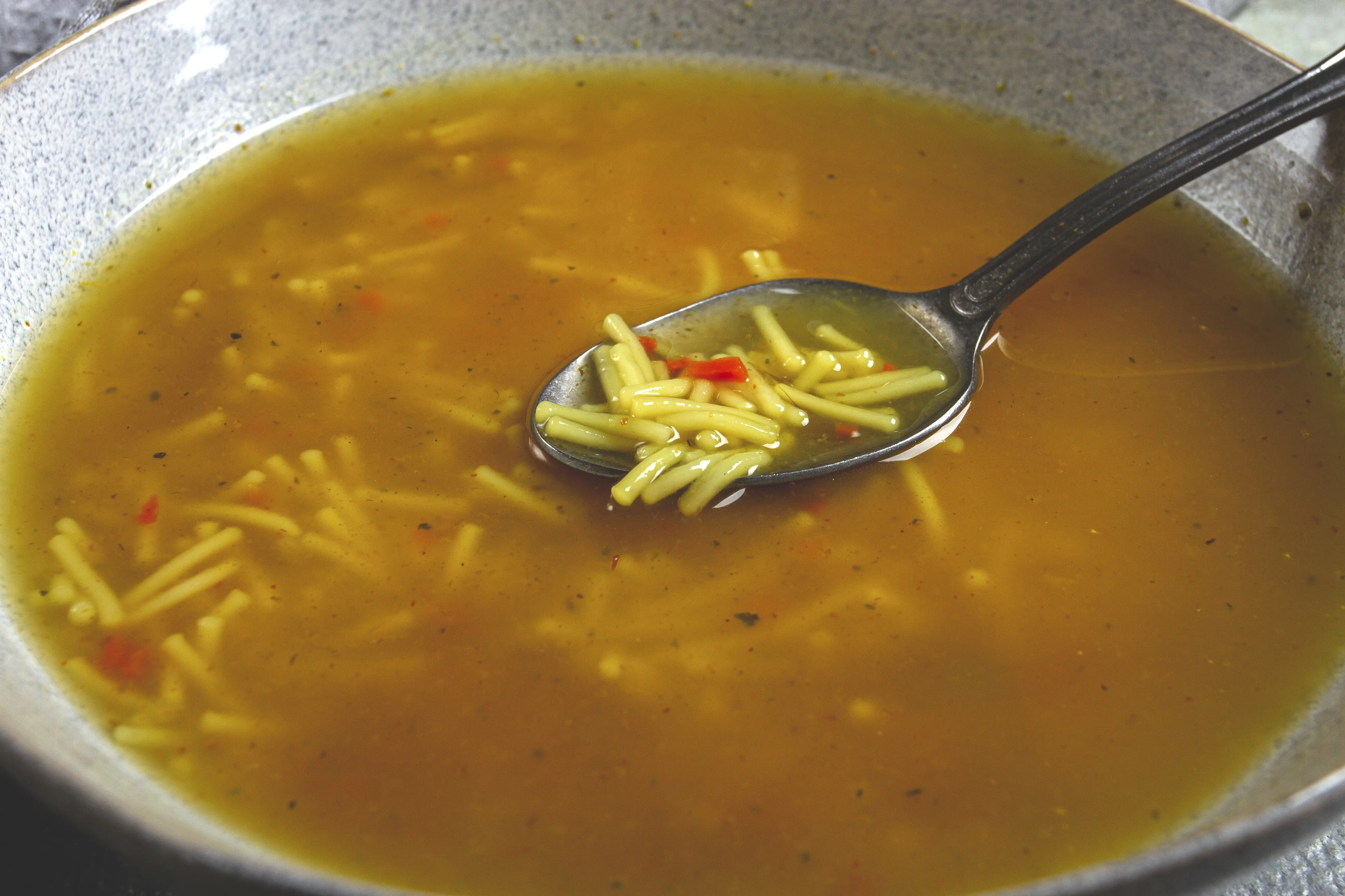 Spoon in bowl of chicken noodle soup