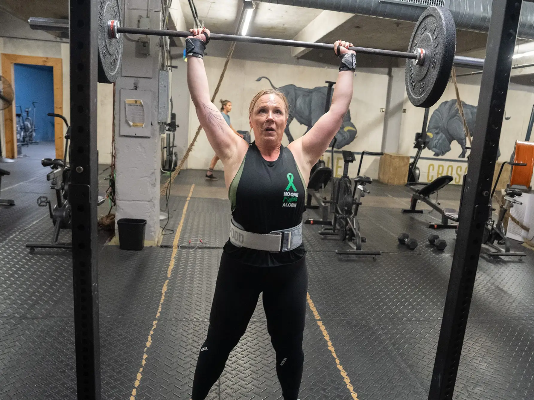 Dr Shernan Holtan lifting weights in the gym performing an overhead barbell press