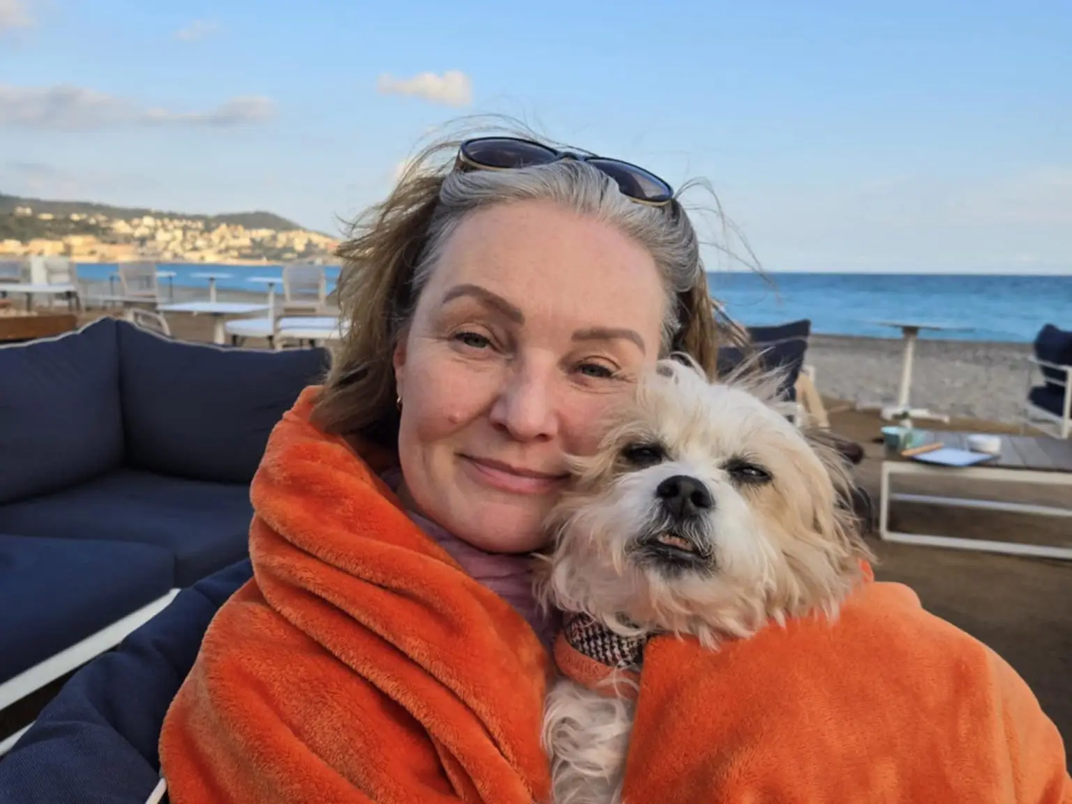 Natalie Lynch and her dog are sitting along the beach.
