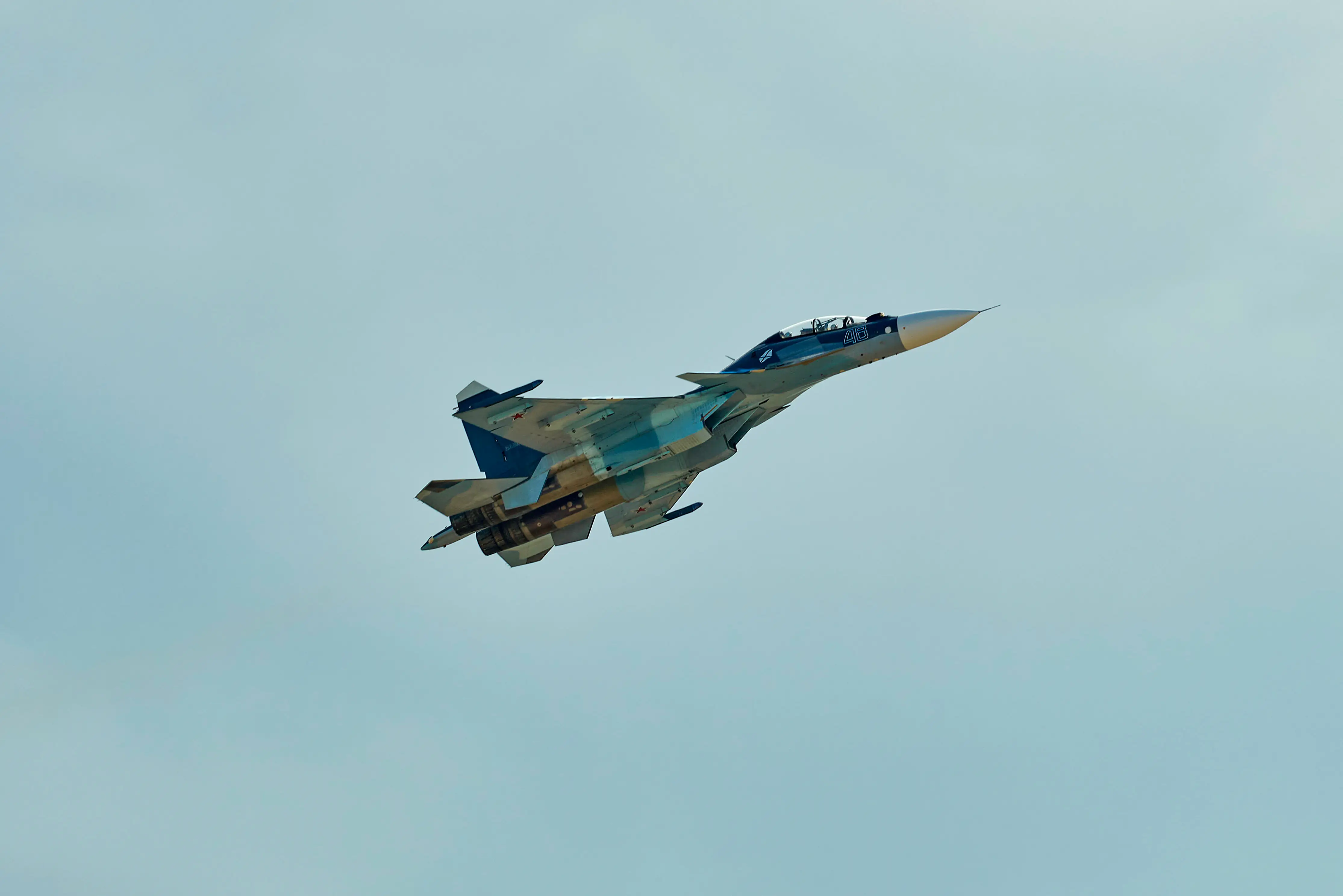 A blue-colored fighter jet in the air