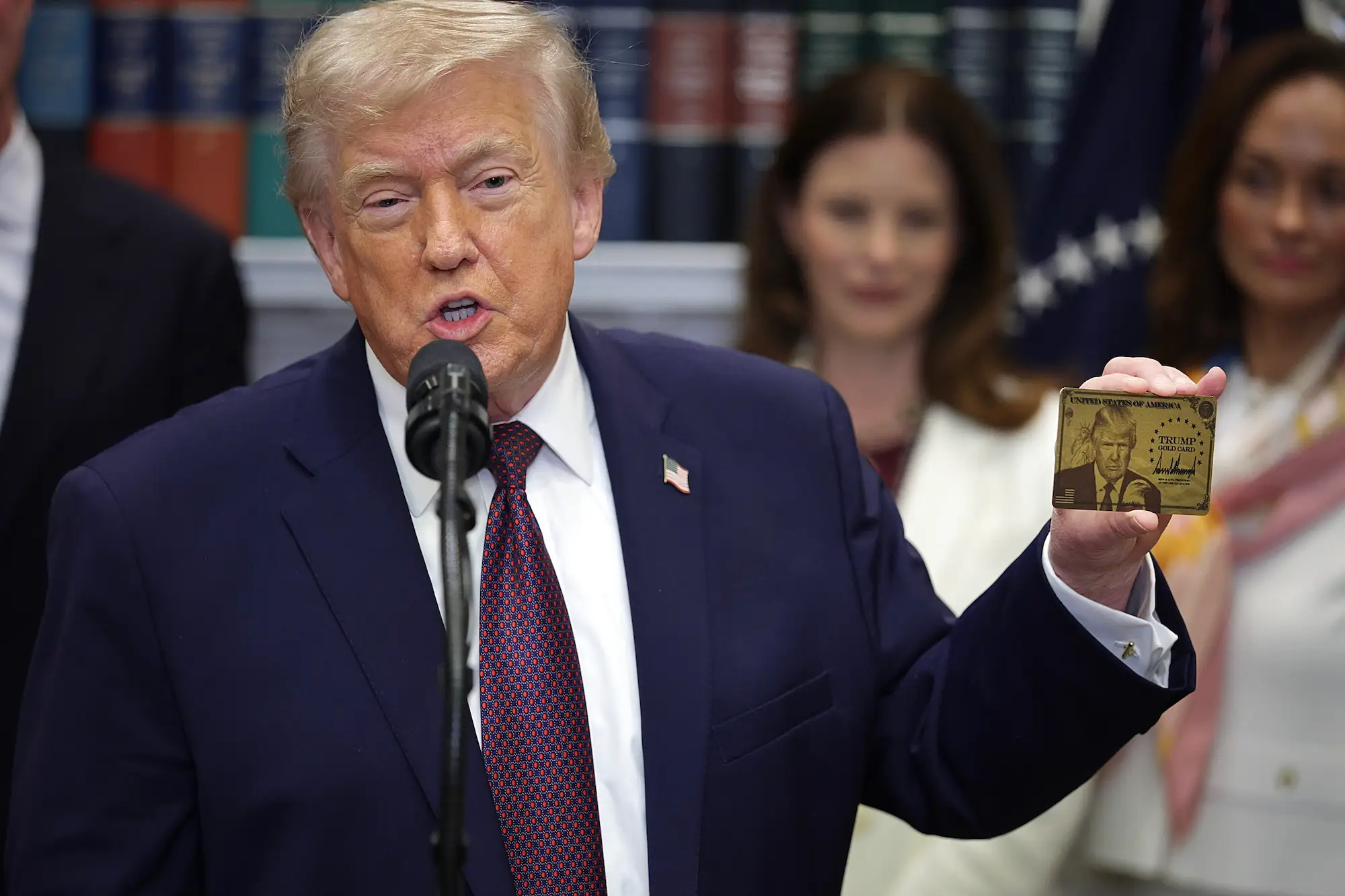 Trump holds up a Trump Gold Card at the White House on Friday, December 19, 2025.