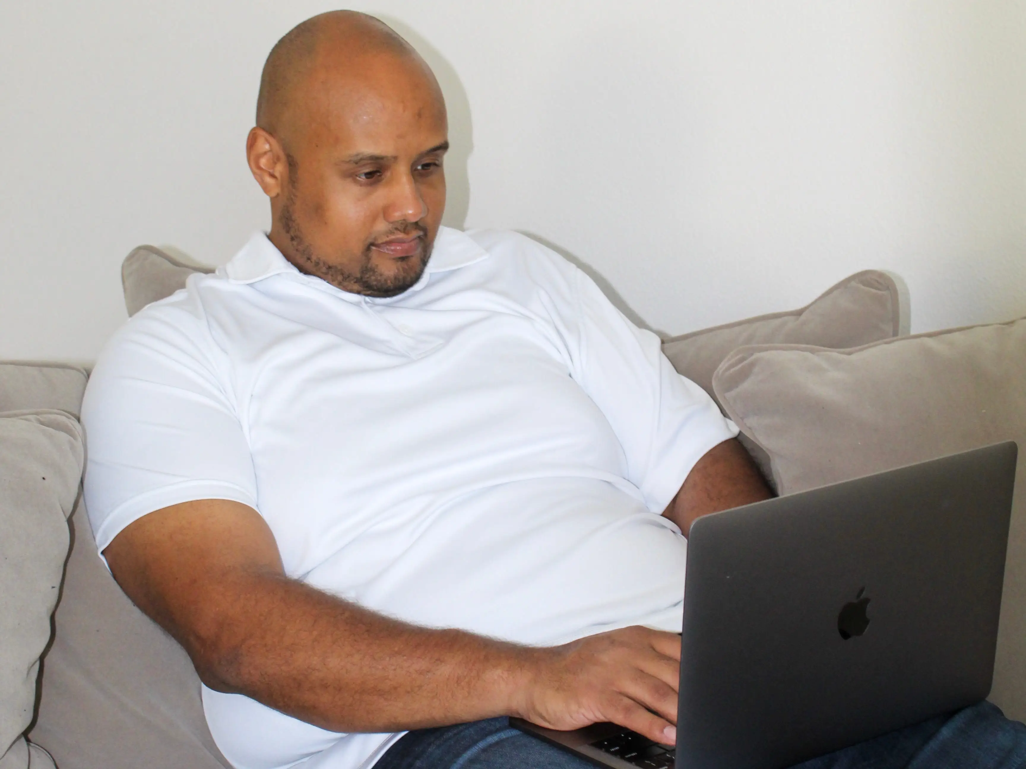 Kimanzi Constable sitting on the couch with his laptop