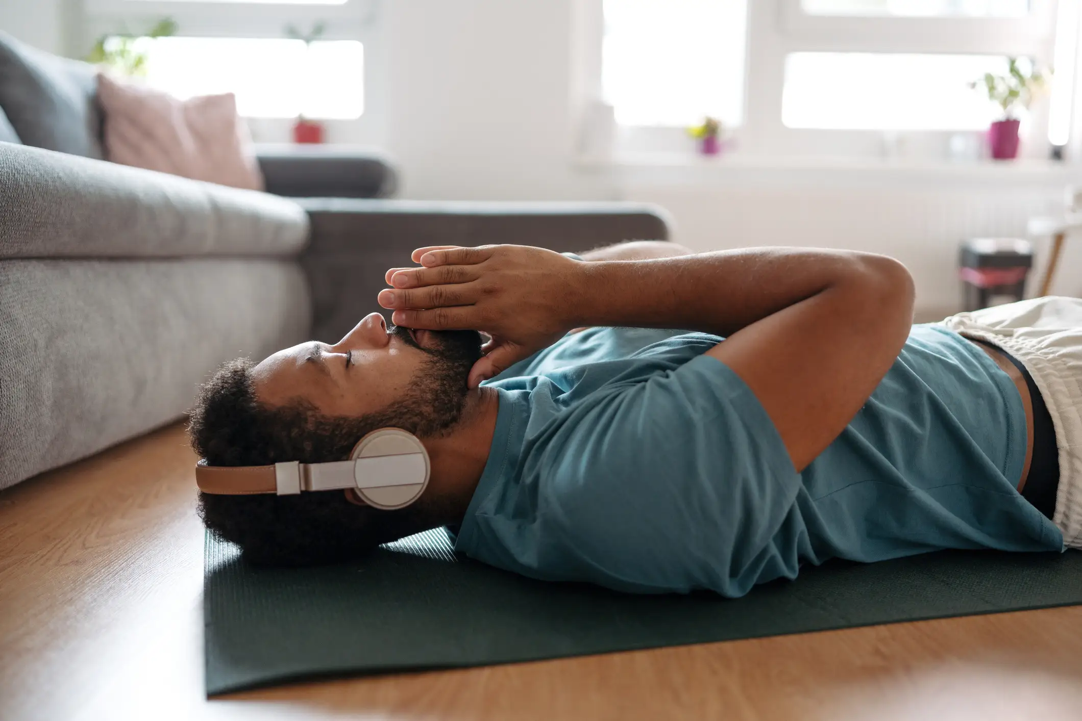 a man lying down on a yoga mat with headphones meditating