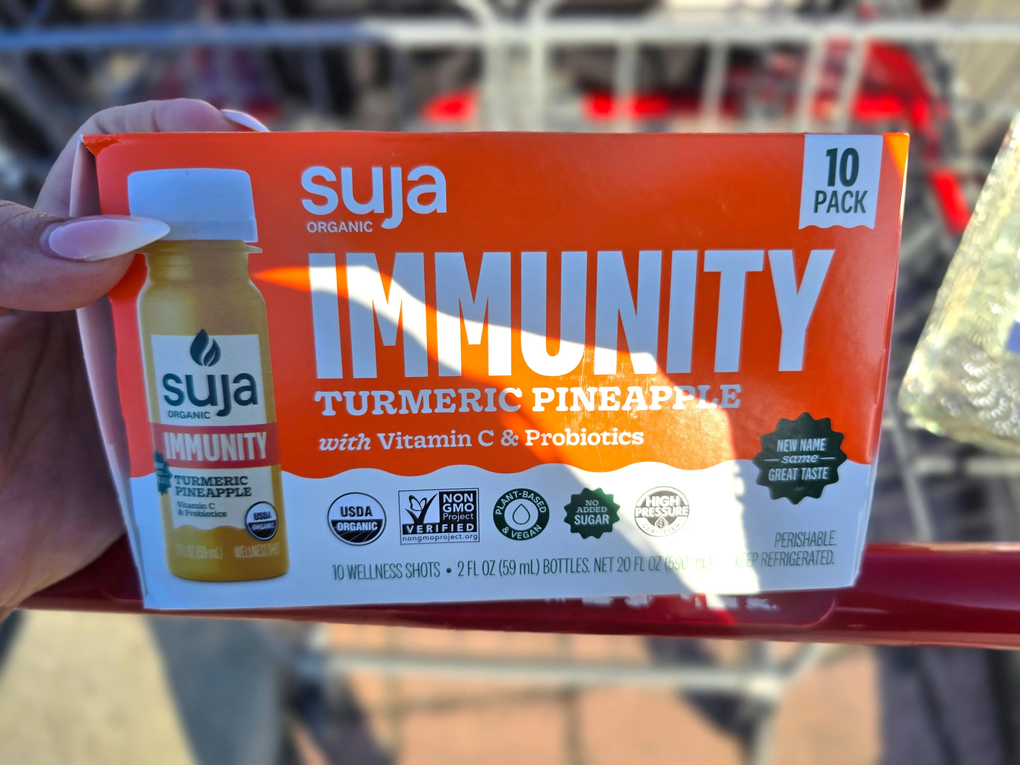 A hand holding a box of Suja organic immunity drinks.