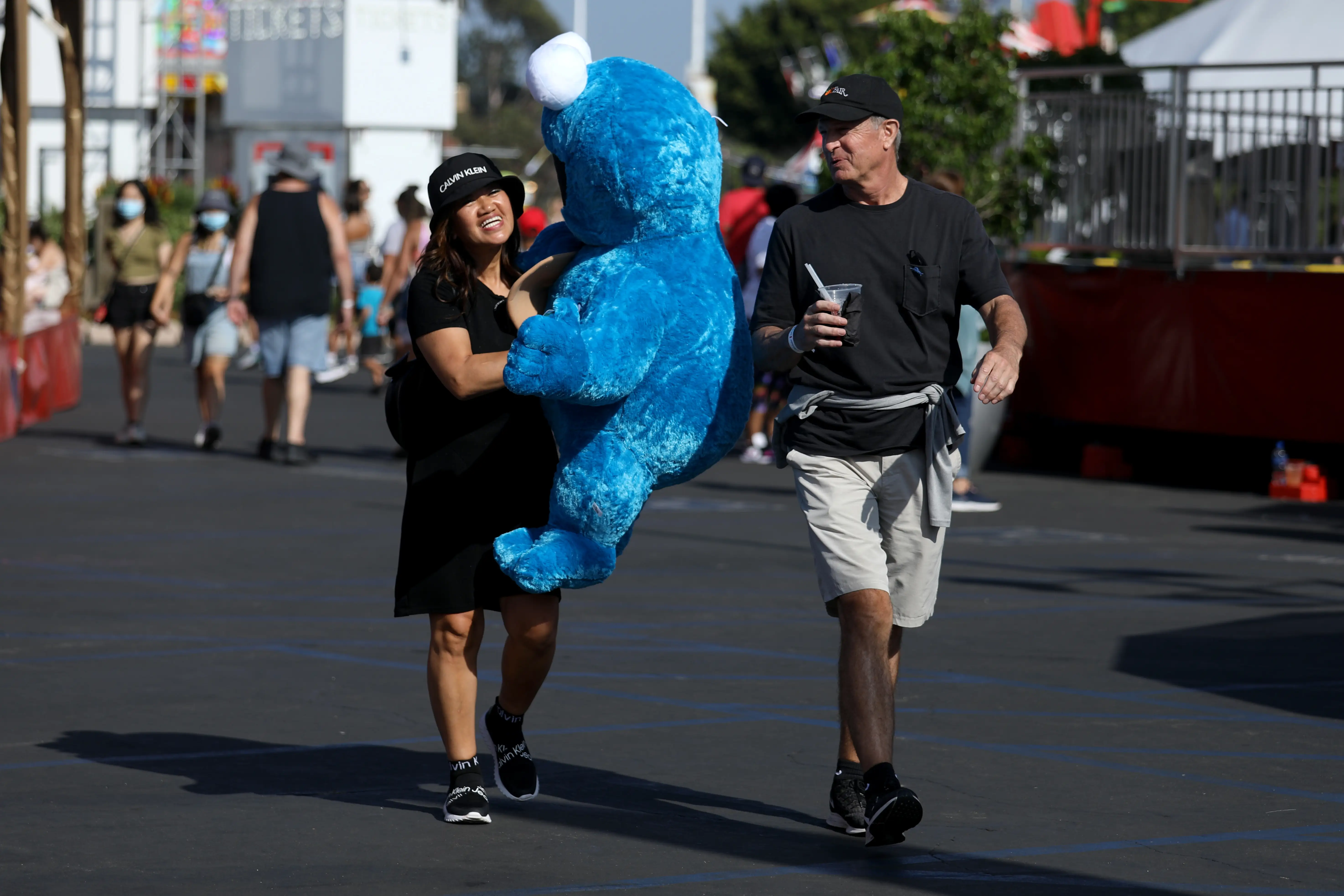Two people walking with a large Cookie Monster doll