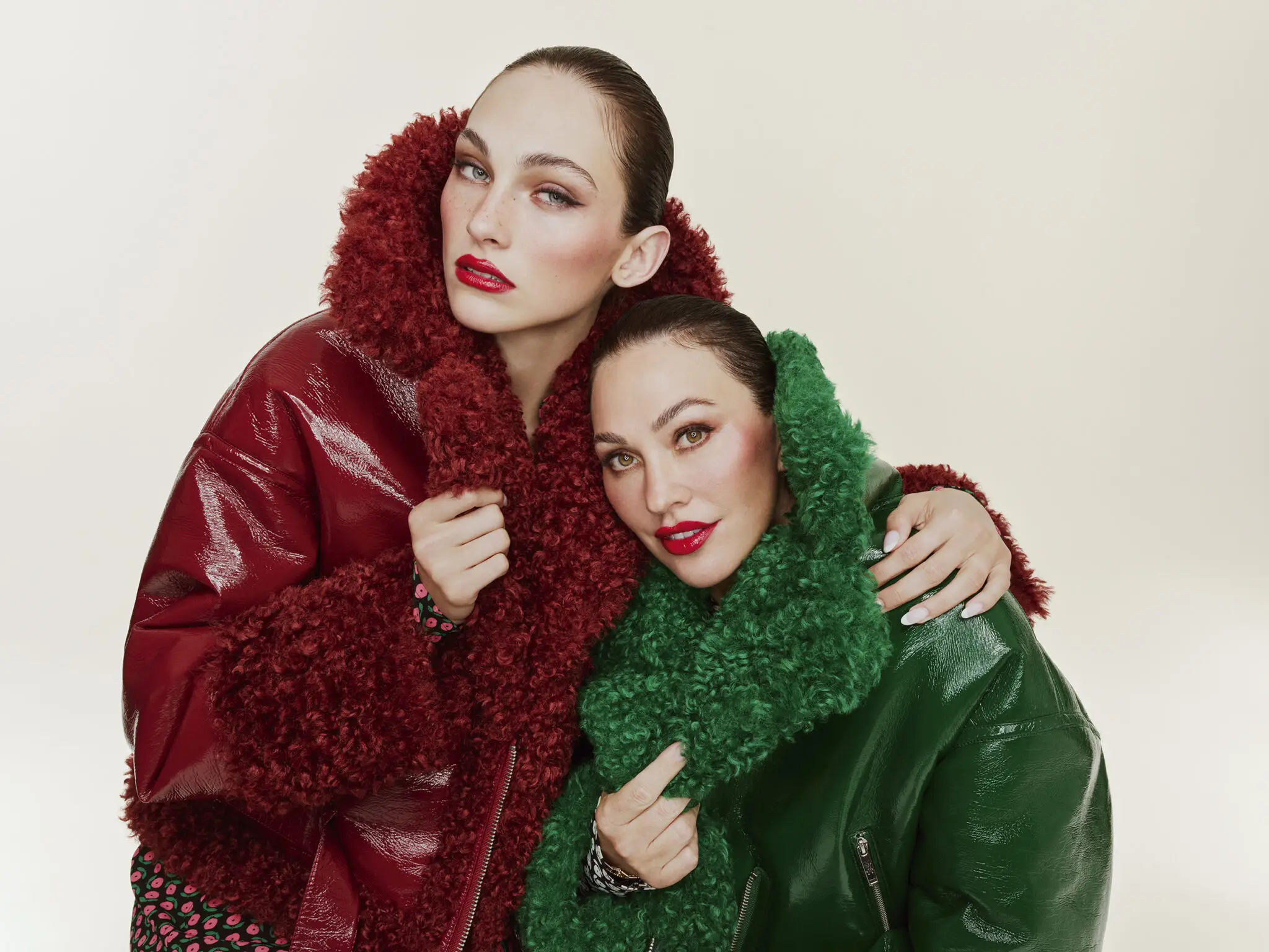 two women pose in a red and green jacket