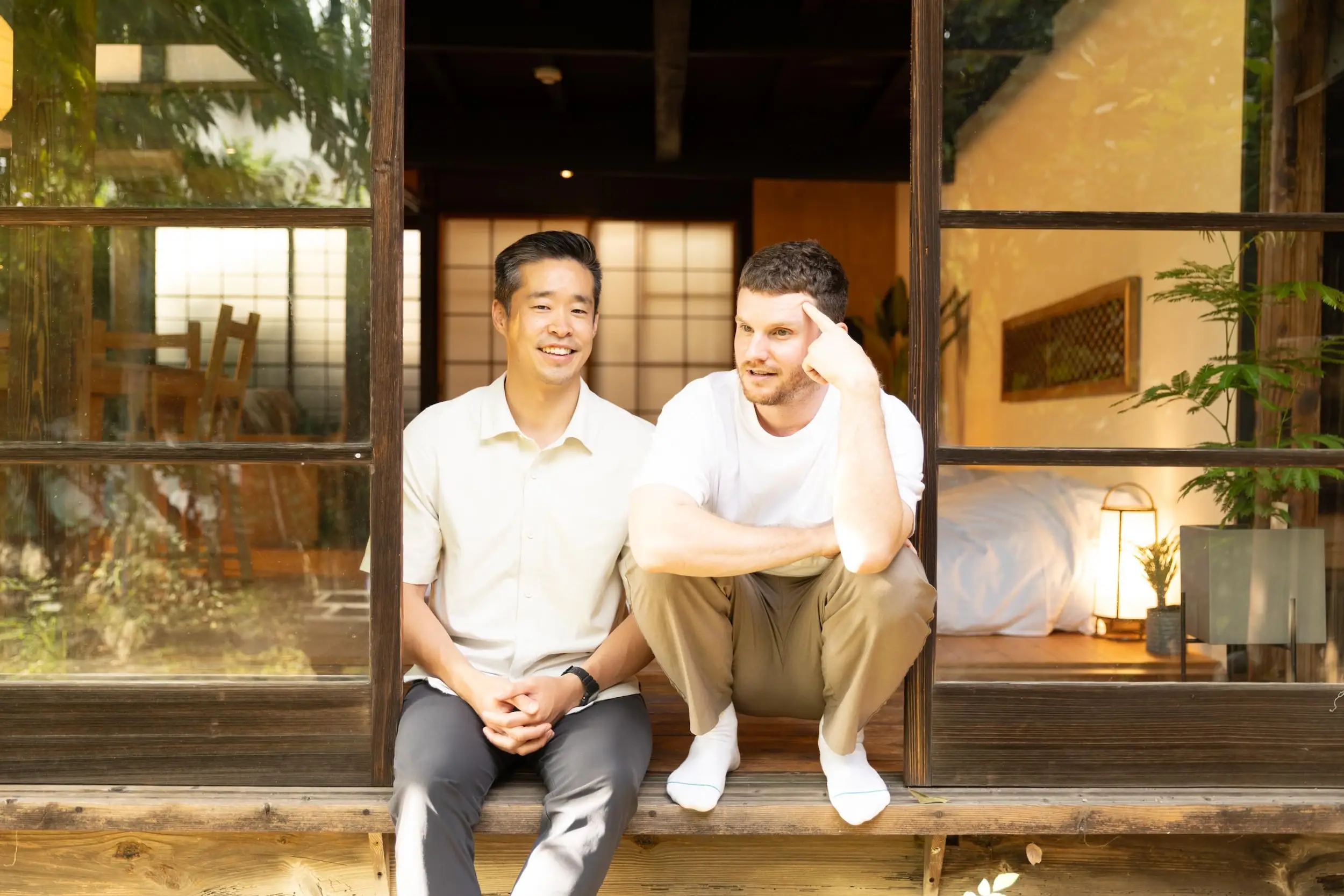 Two men setting on a stop outside of a home.