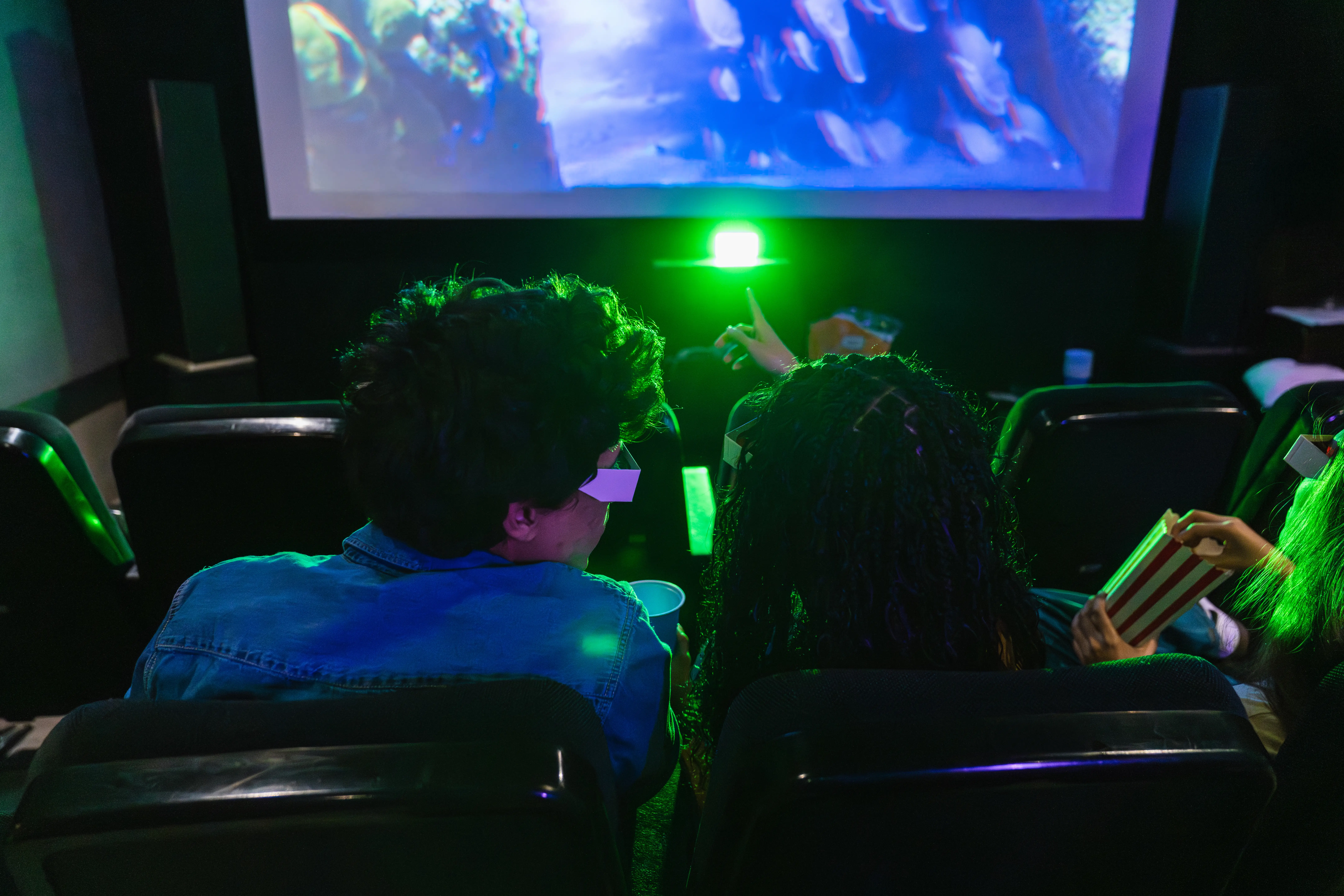 gen zers wearing 3D glasses at the movies and pointing to the screen