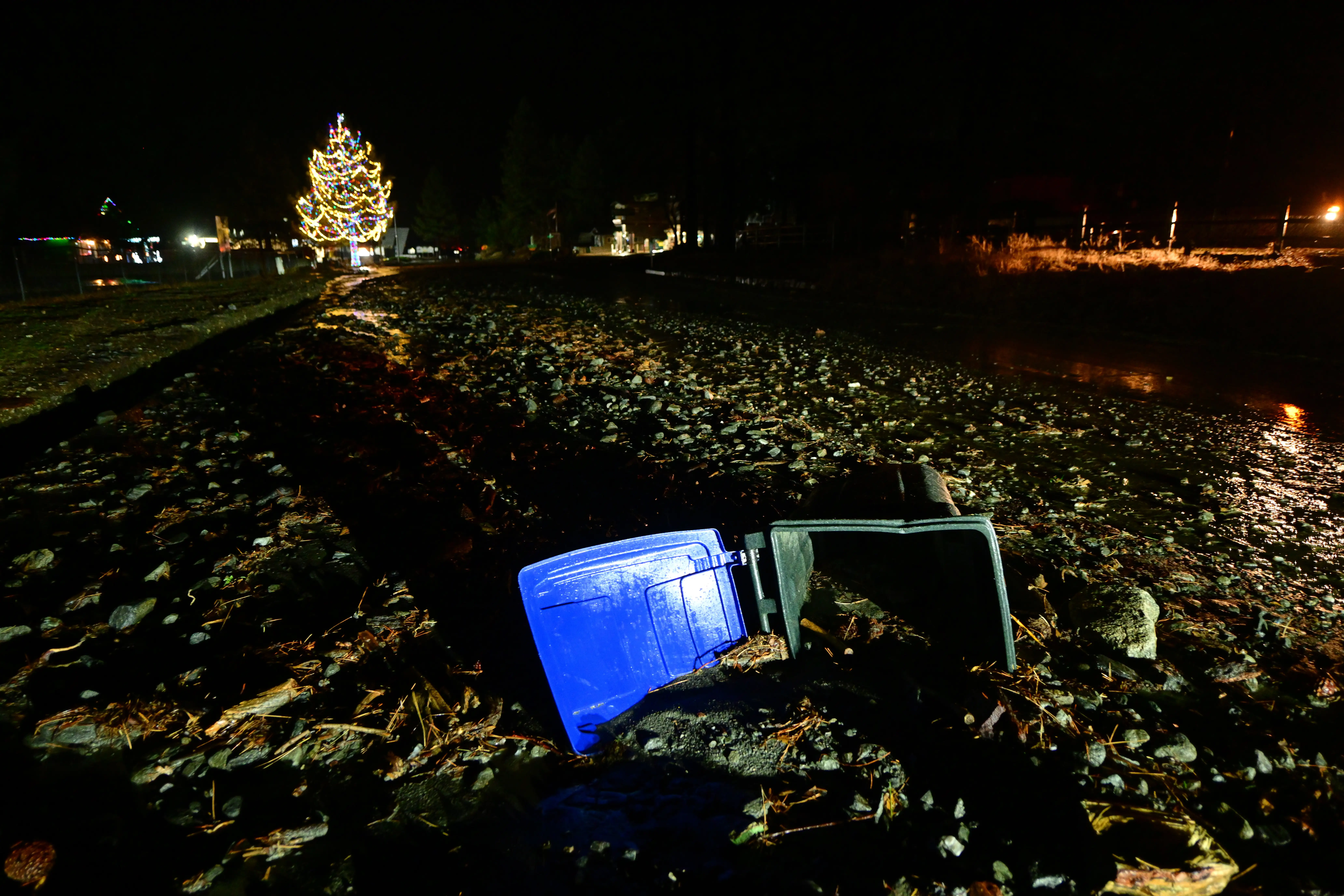 A trashcan lies stuck in mud on California State Route 2 after flooding Wednesday, Dec. 24, 2025, in Wrightwood, Calif.