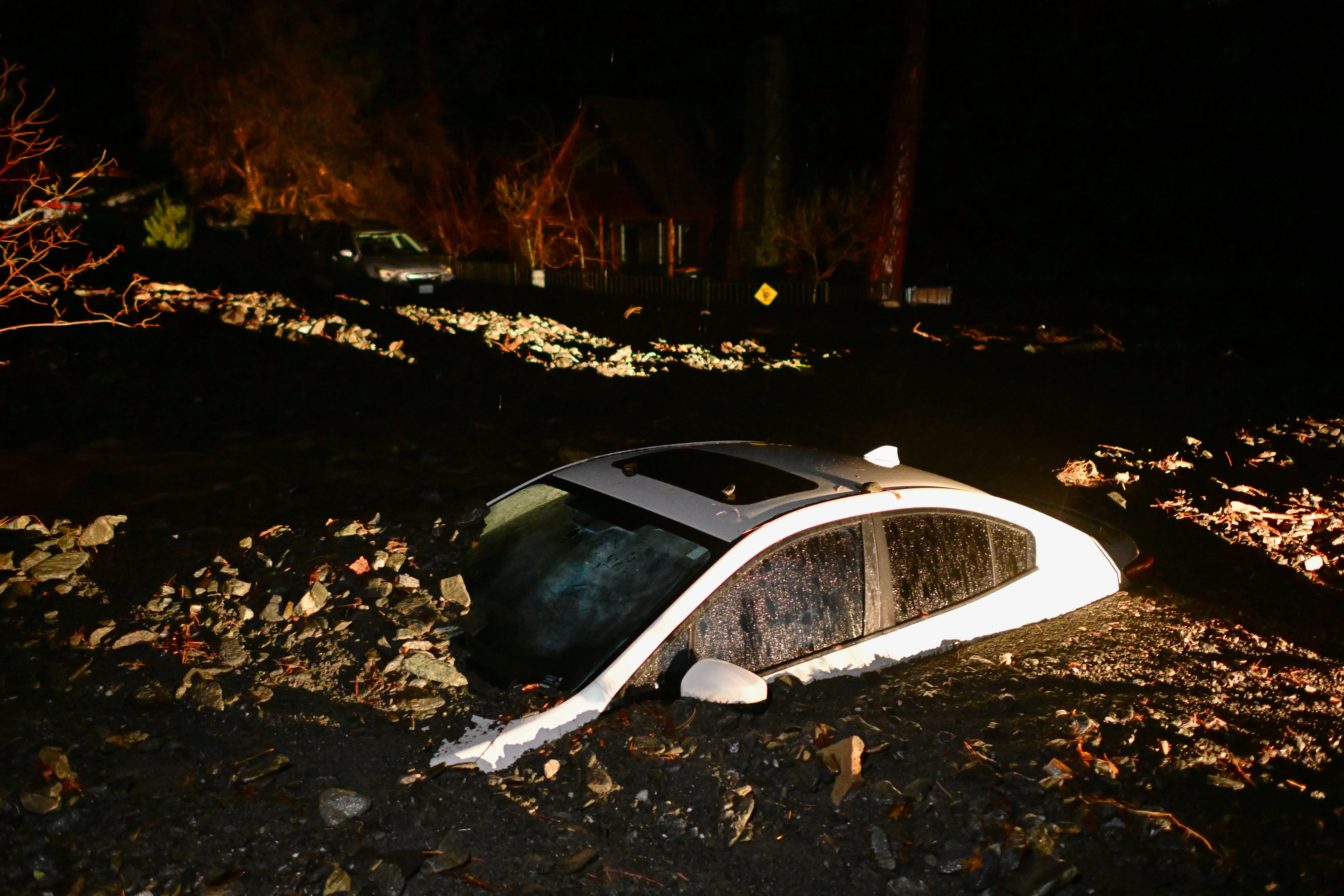 A car sits buried in mud after flooding Wednesday, Dec. 24, 2025, in Wrightwood, Calif.