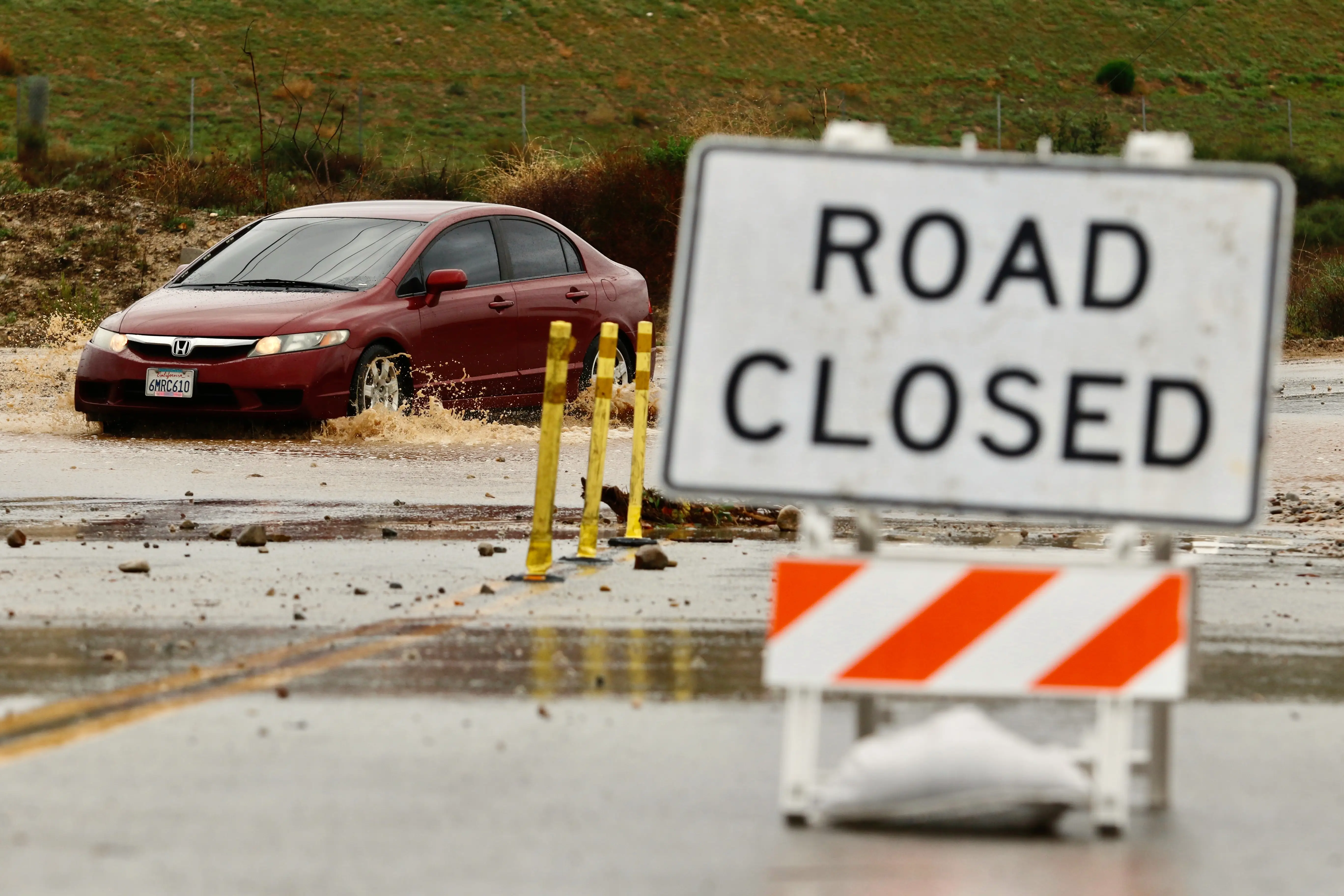 A driver goes though a road closed for flooding, Wednesday, Dec. 24, 2025, in in Valencia, Calif.