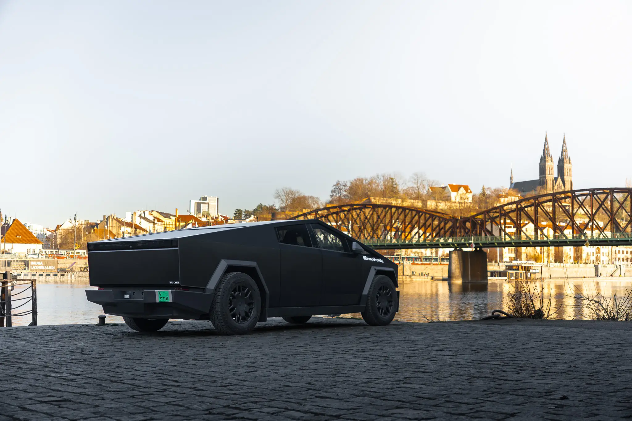 A Tesla Cybertruck parked by a river in Prague.