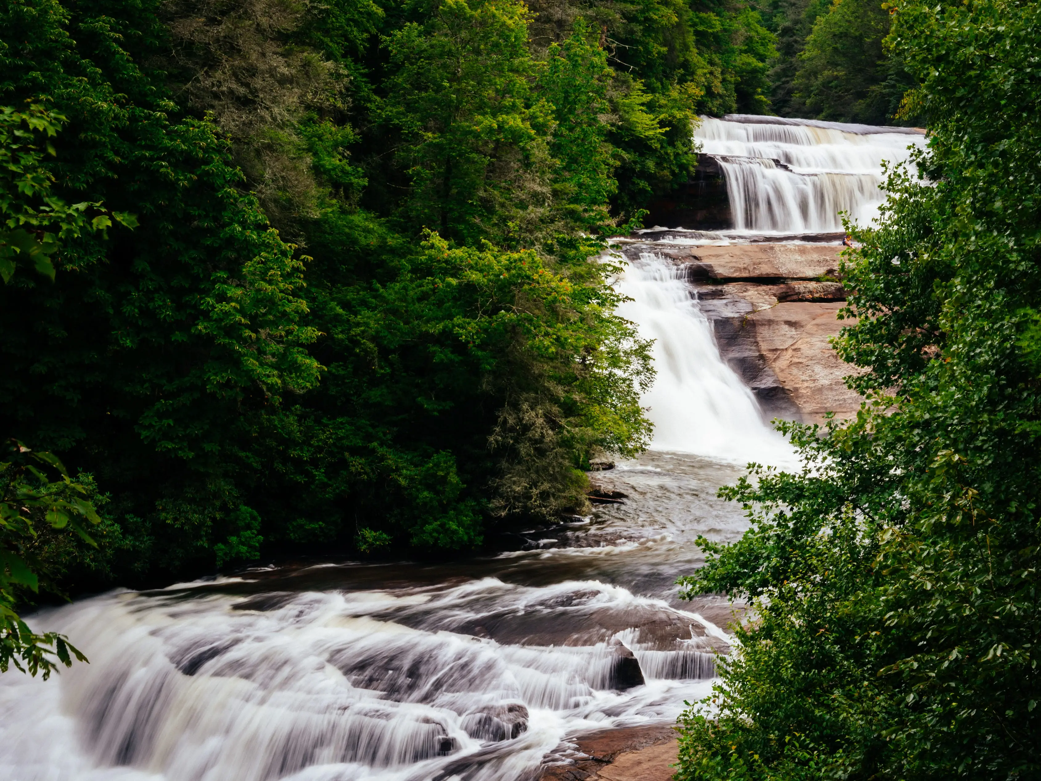 A three-level waterfall surrounded by trees.