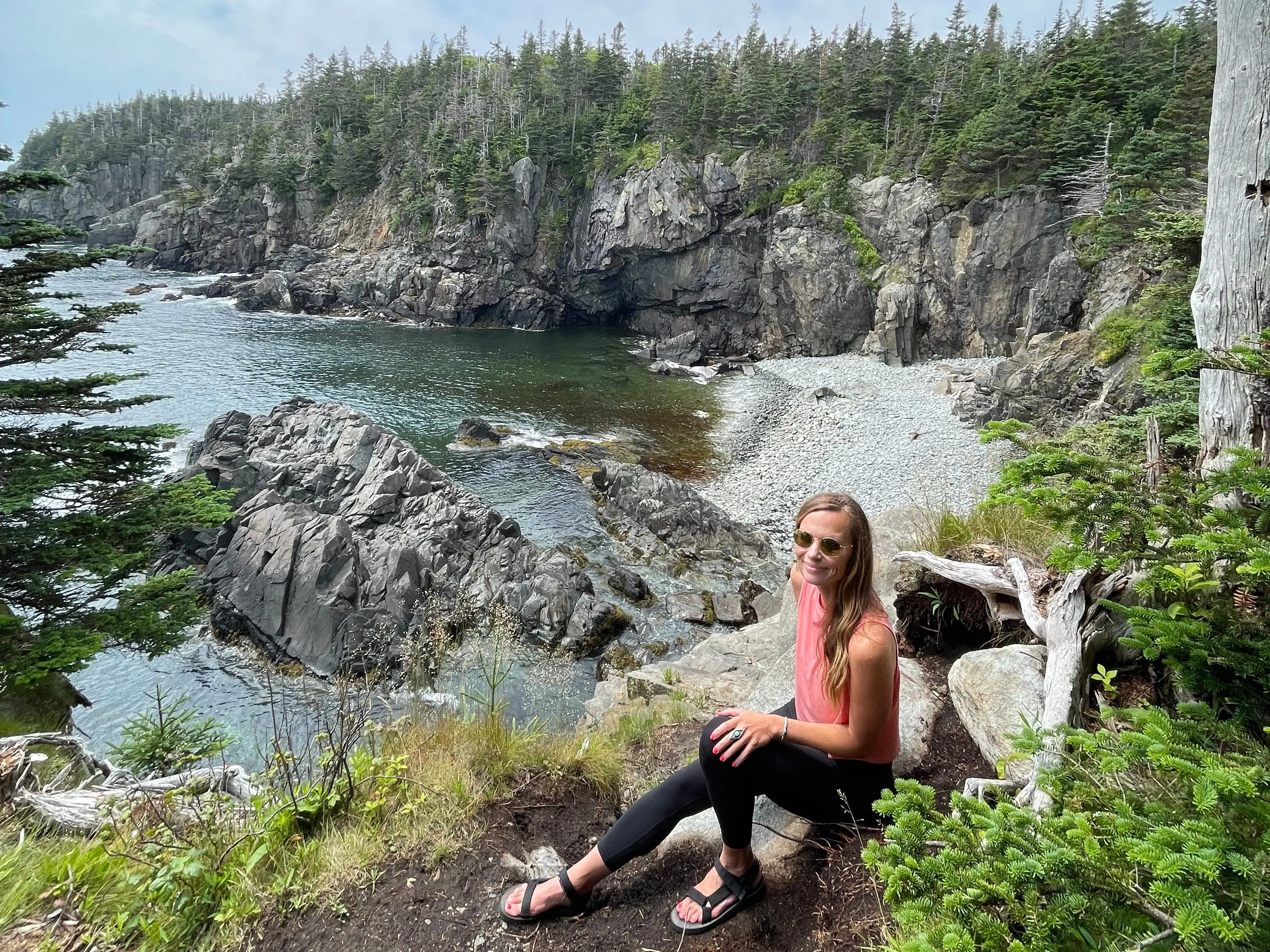Emily sits near a cliff in Quoddy Head State Park in Maine.