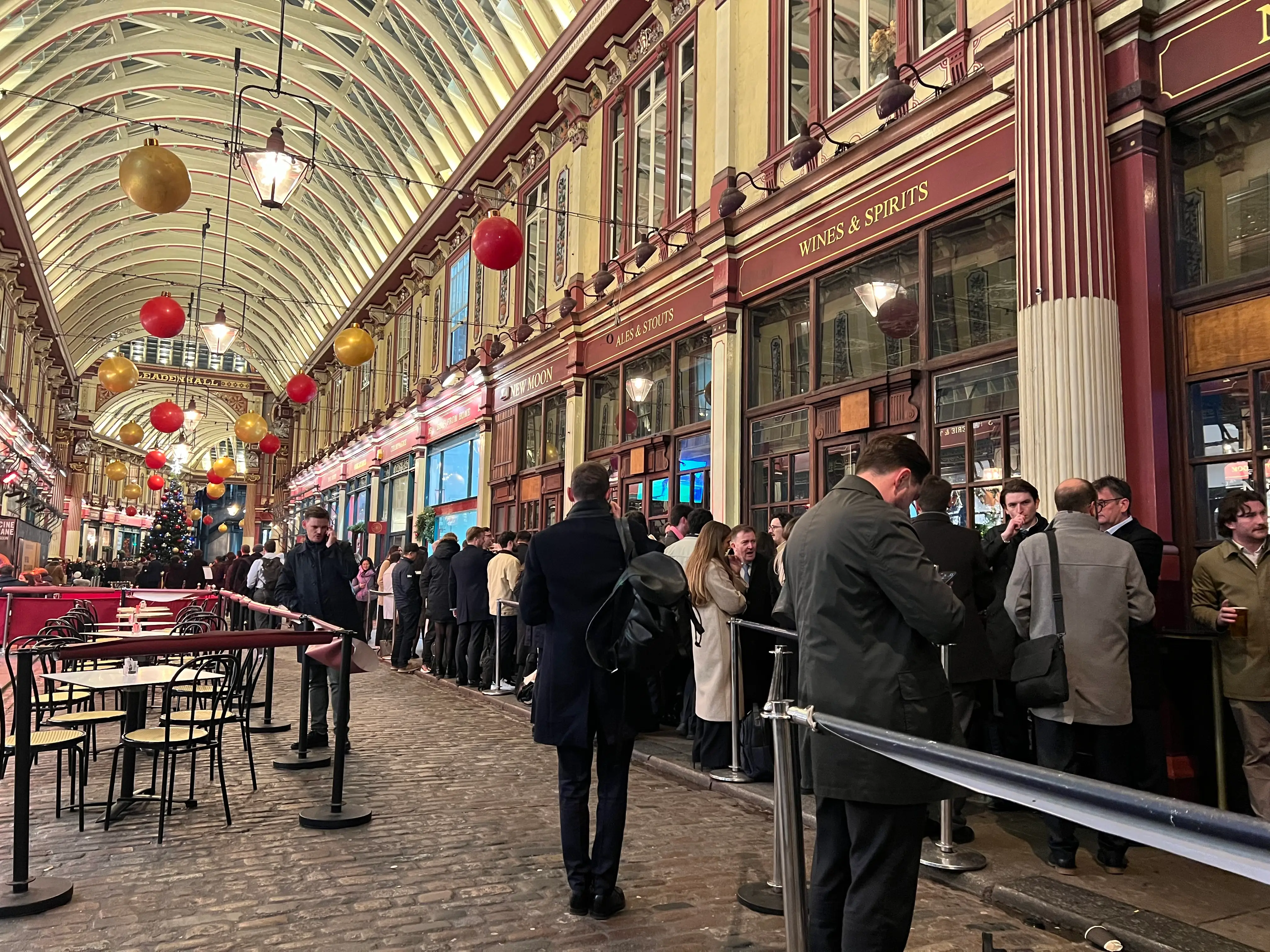 Drinkers stand in the vaulted halls of the City of London's Leadenhall Market.