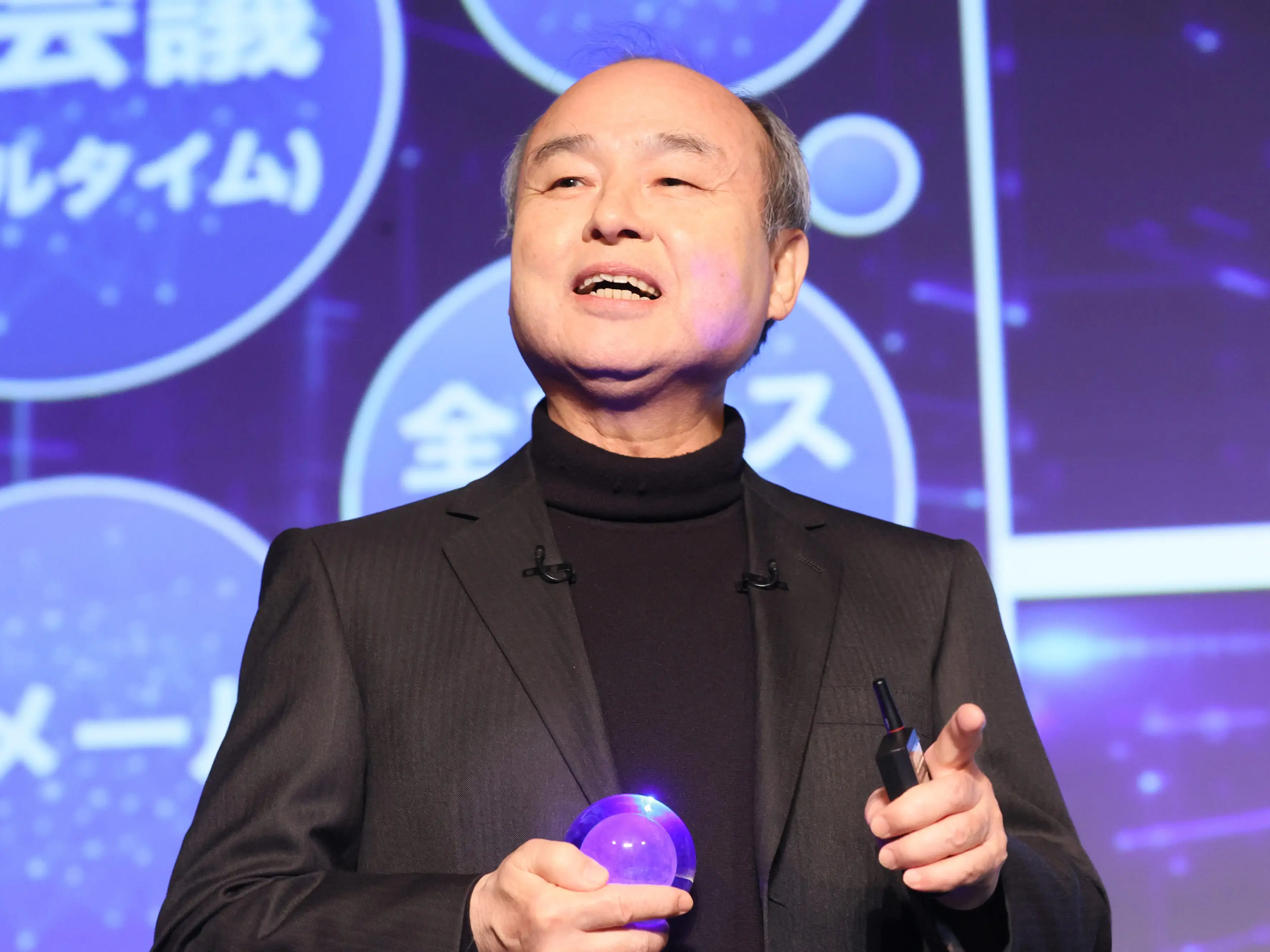 Neon light reflects on Masayoshi Son.
