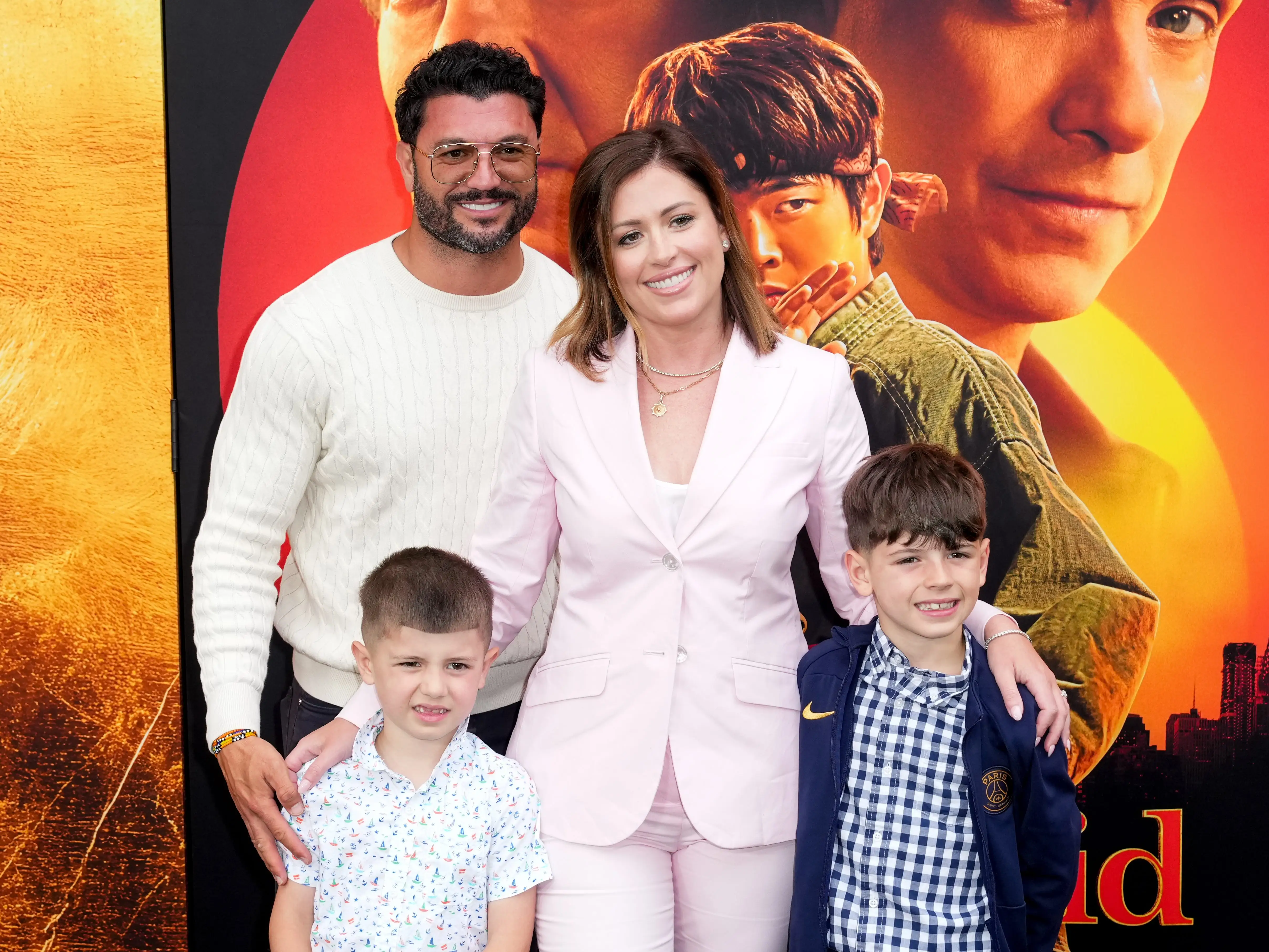 A family of four poses in front of a movie poster.