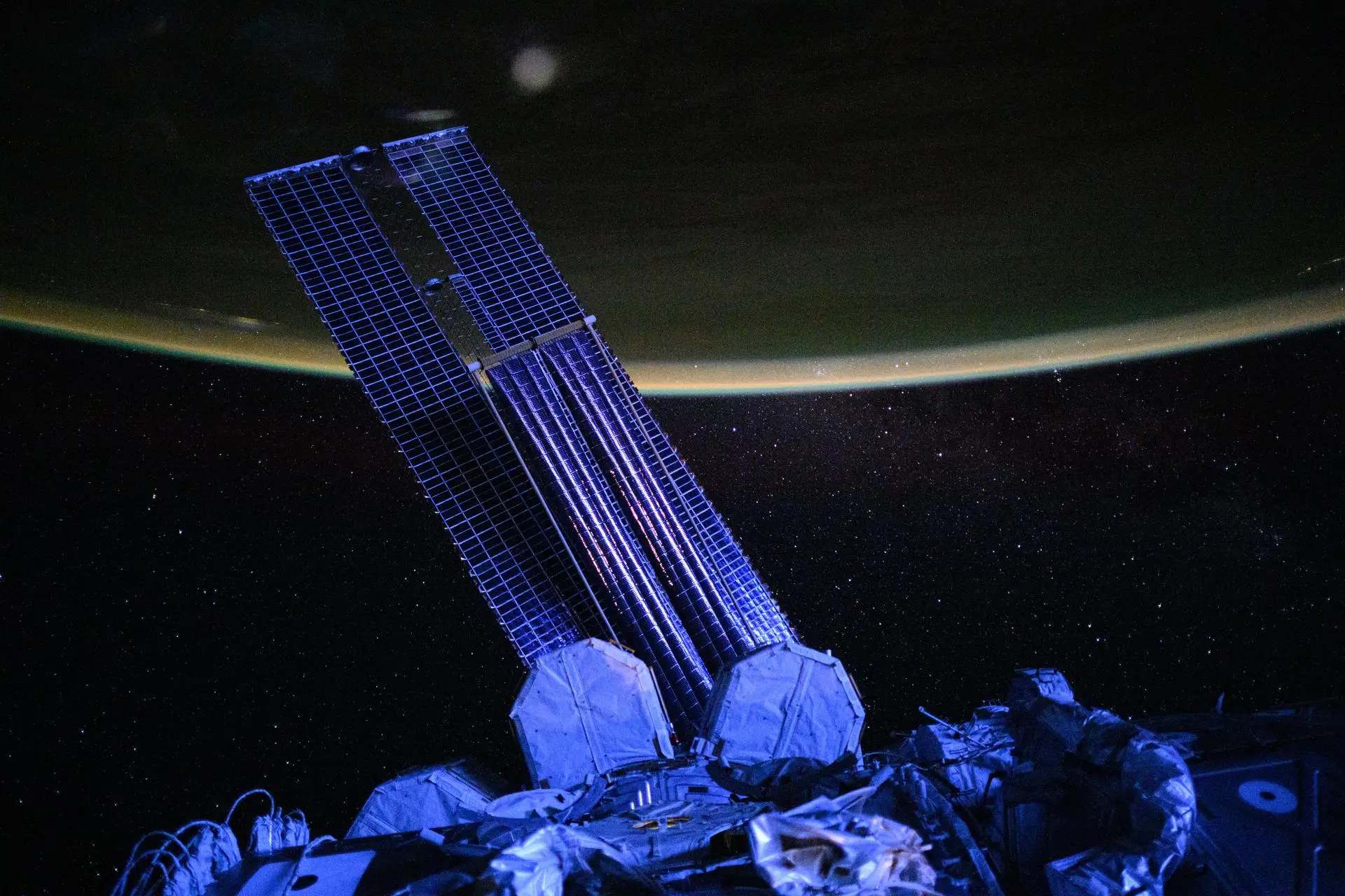 The main solar arrays of the ISS look violet as it orbits above New Zealand in September 2025.
