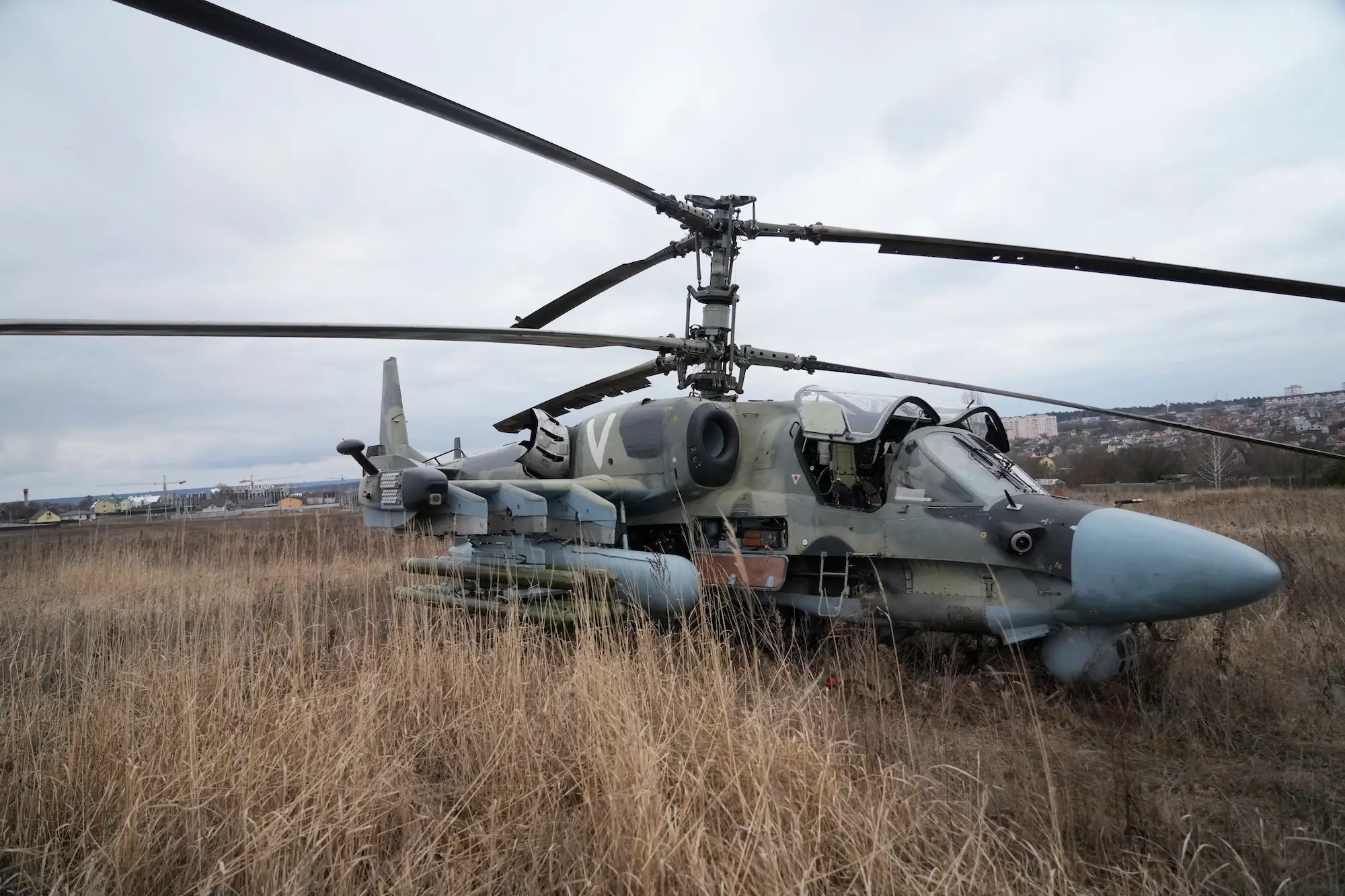 A grey and green helicopter in a straw-colored field