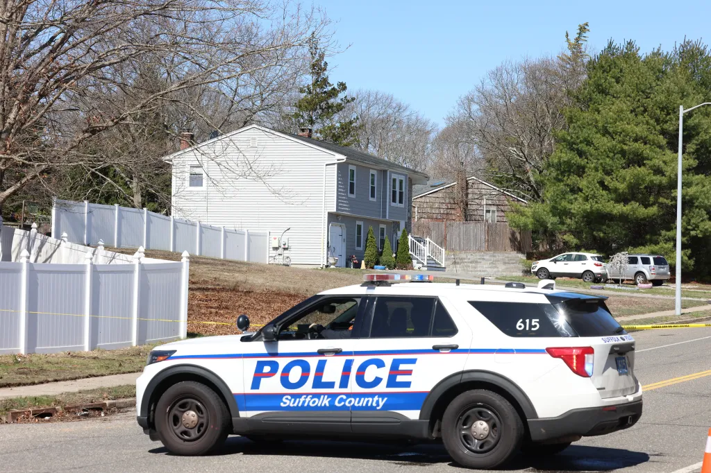 Suffolk County Police car parked in front of a house, investigating an incident where a 15-year-old allegedly stabbed his mother and grandmother.