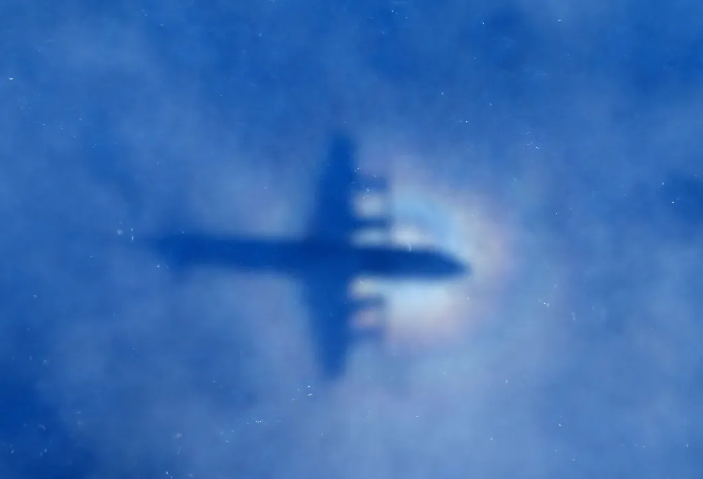 Blurred silhouette of an airplane against a blue sky.
