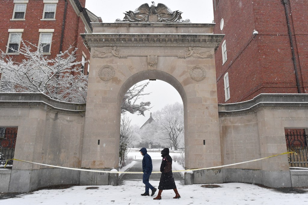 Passers-by walk past crime scene tape at an entrance to Brown University, Sunday, Dec. 14, 2025, in Providence, R.I., following the Saturday, Dec. 13, shooting at the university.