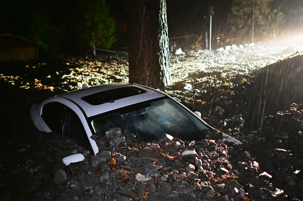 A car sits buried in mud after flooding Wednesday, Dec. 24, 2025, in Wrightwood, Calif.