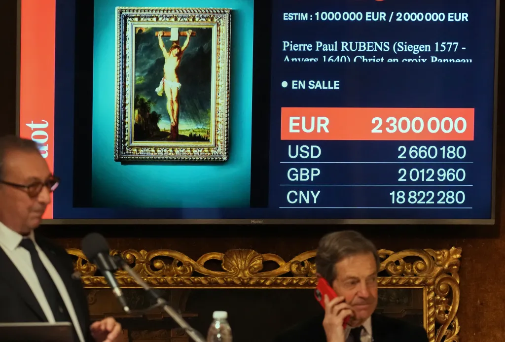 A large screen at an auction displays a painting of Christ on the cross by Pierre Paul Rubens, with a final bid of 2,300,000 EUR shown alongside other currencies.