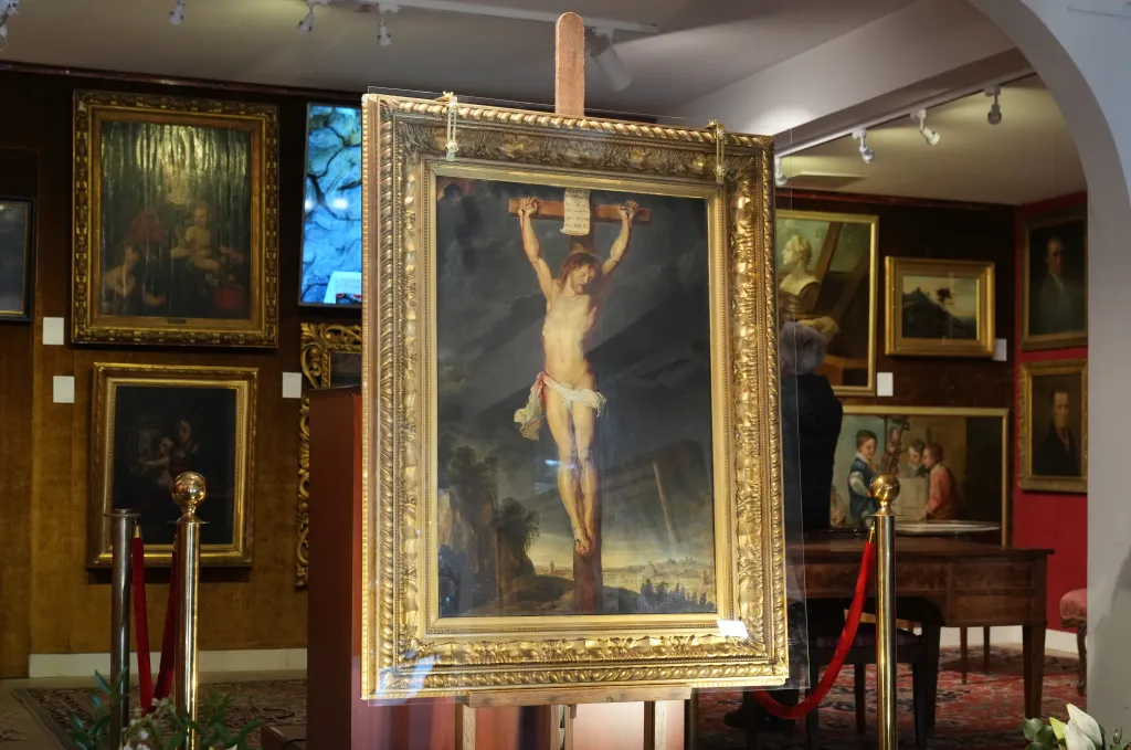 A painting of Christ on the cross in a gilded frame on an easel at the France Rubens Auction.