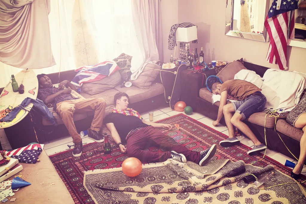 Three men asleep in a messy living room after a party.