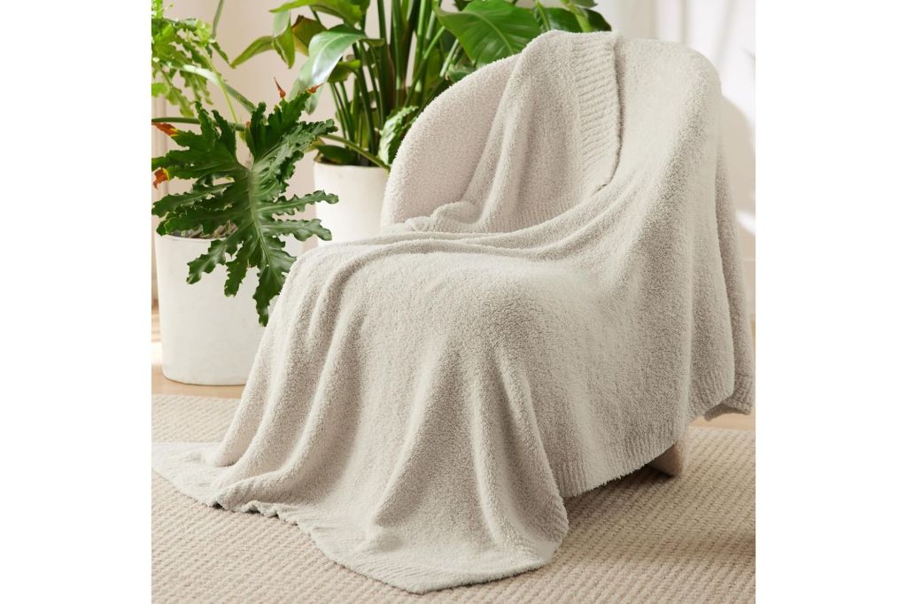 A throw blanket on a chair surrounded by plants.