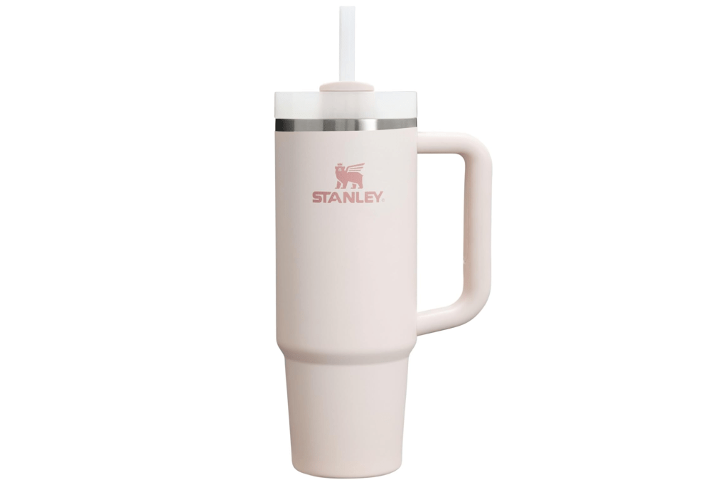 A light pink Stanley Quencher Flowstate tumbler with a straw and handle.