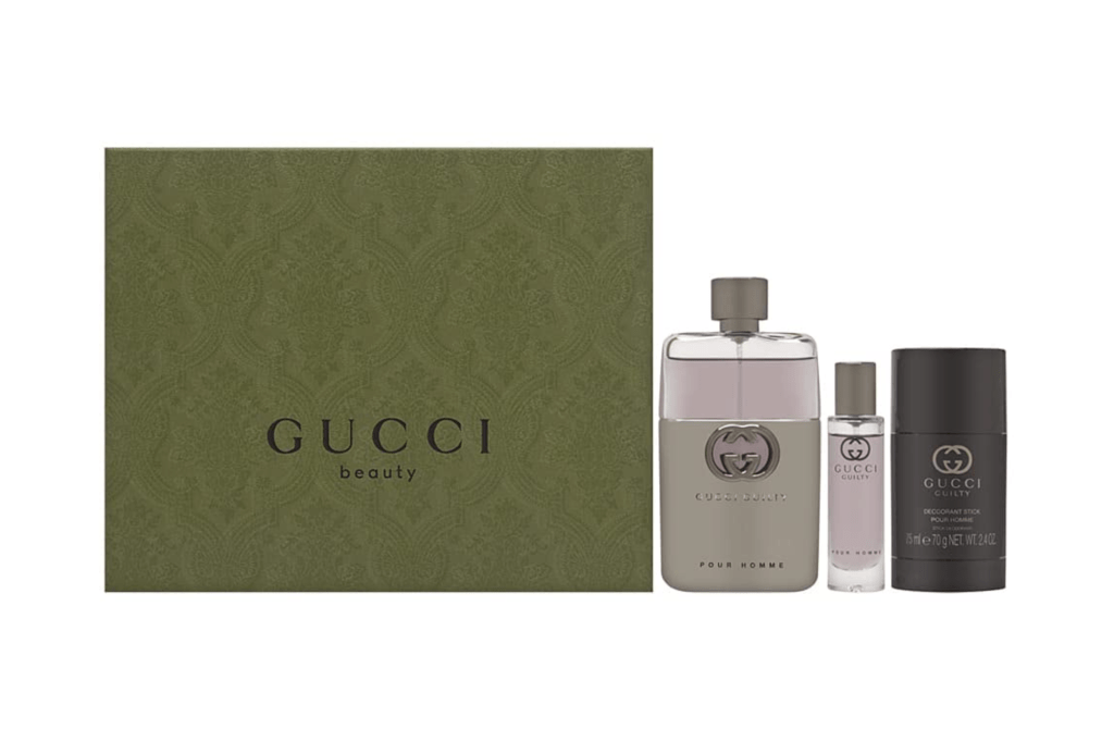 Gucci Guilty Pour Homme fragrance set with a dark green box, a gray bottle of cologne, a small bottle of travel spray, and a deodorant stick.